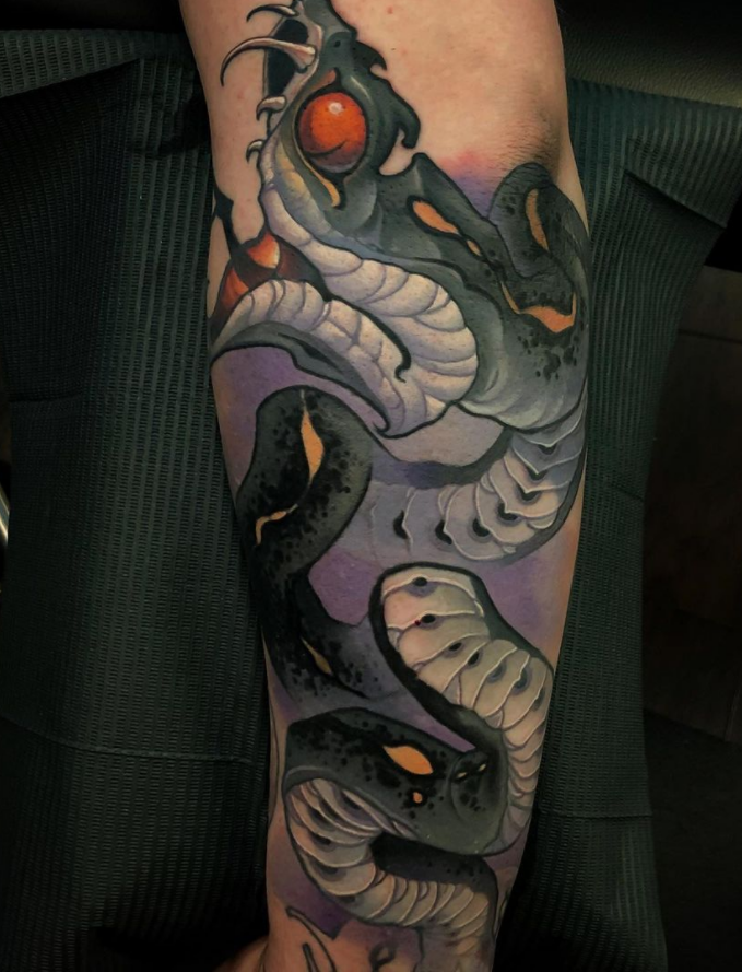 Tattoo of a black and white snake with orange accents and red eyes on a person's arm.