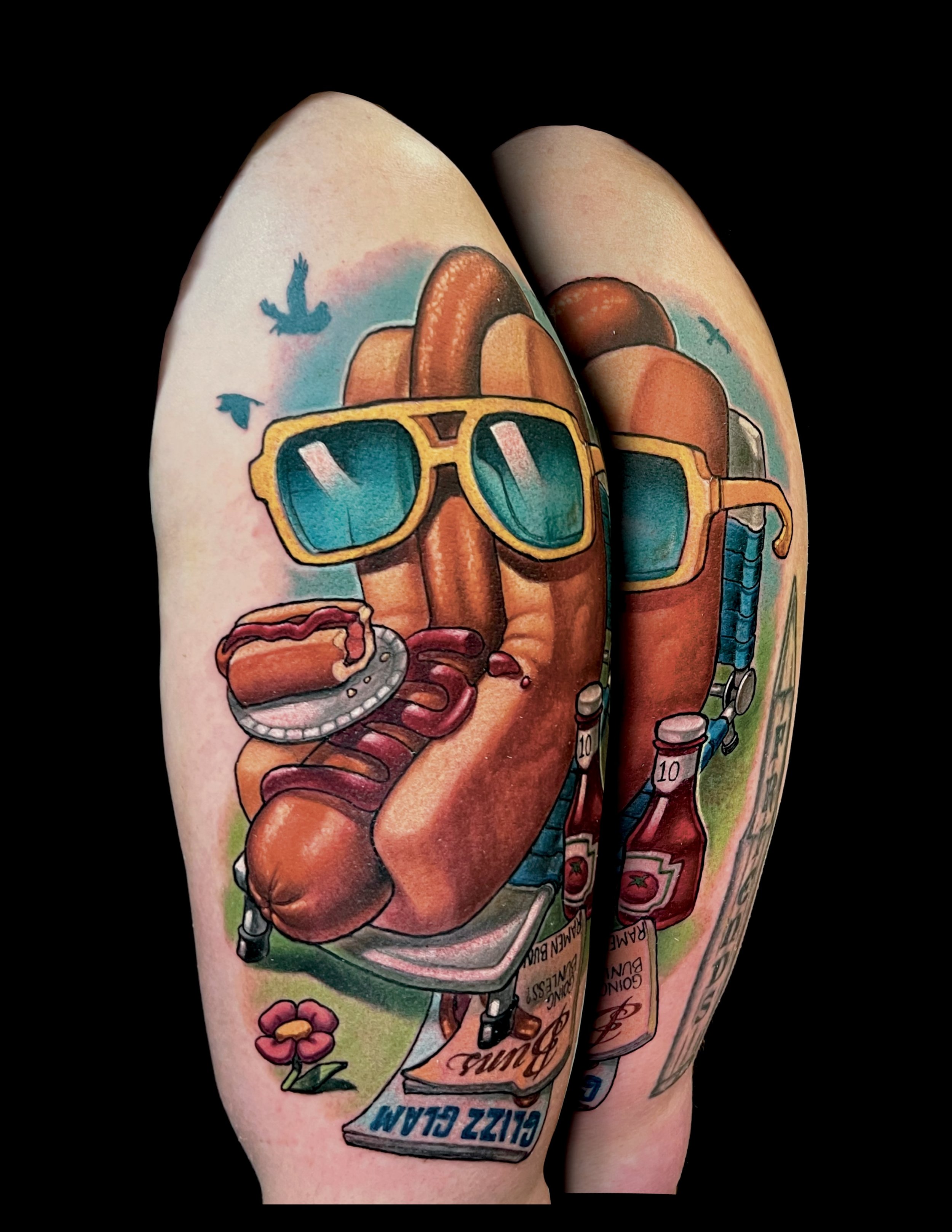 Colorful tattoo of a vintage stove with a frying pan, with a pineapple in the background, sunglasses, and handwritten text, on person's arm against black background.