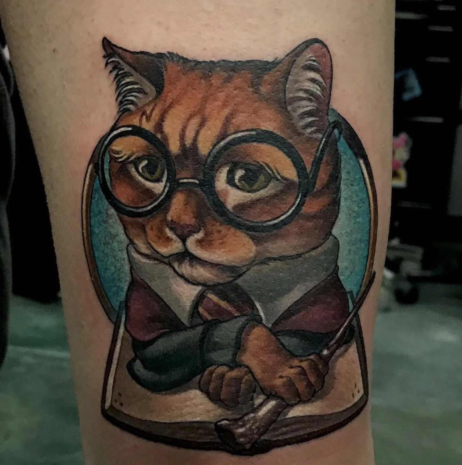 Colorful tattoo of a cat wearing glasses on a person's arm.