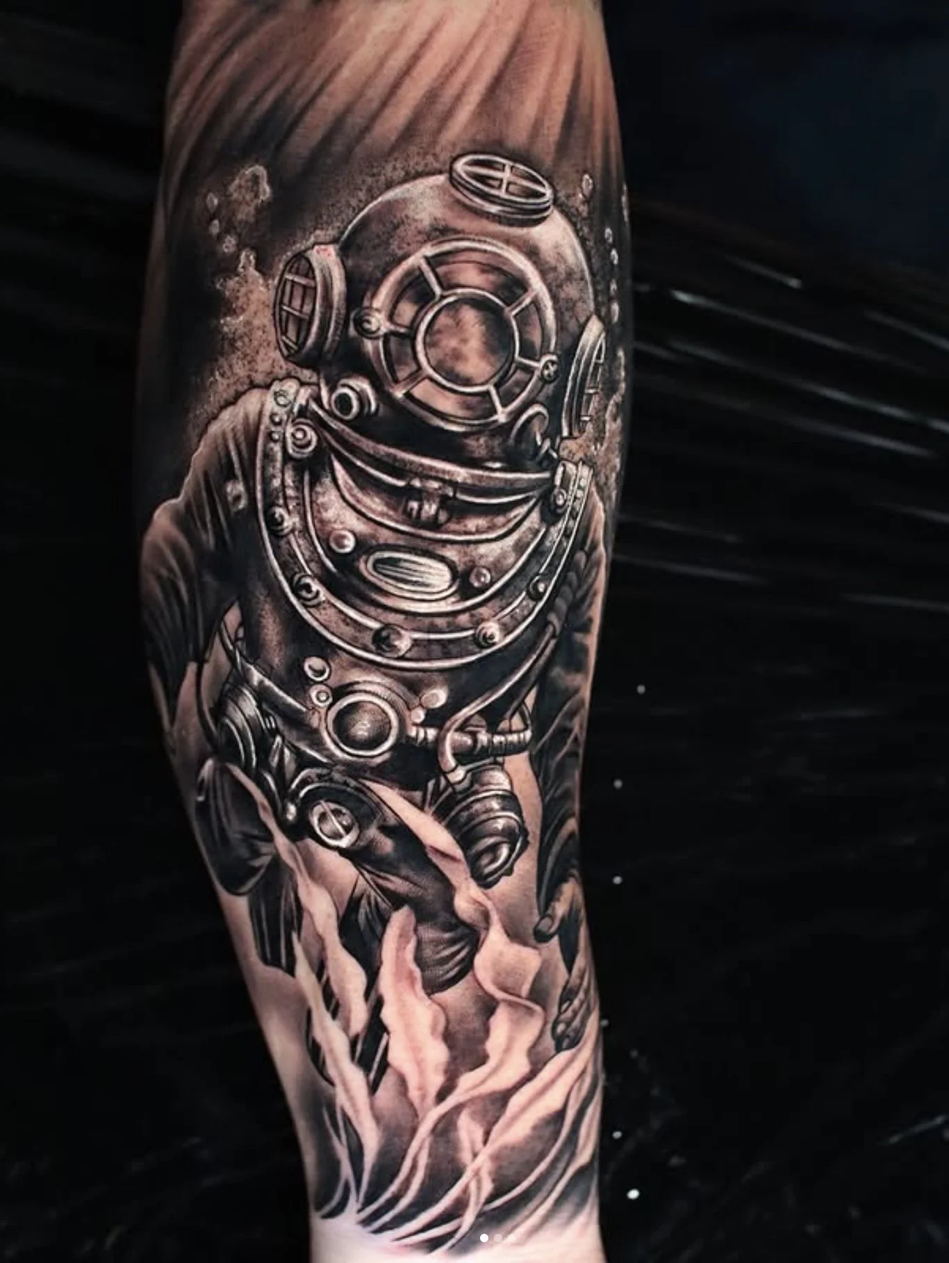 Black and gray tattoo of a vintage deep-sea diver helmet on a person's arm, with detailed shading and realistic style.