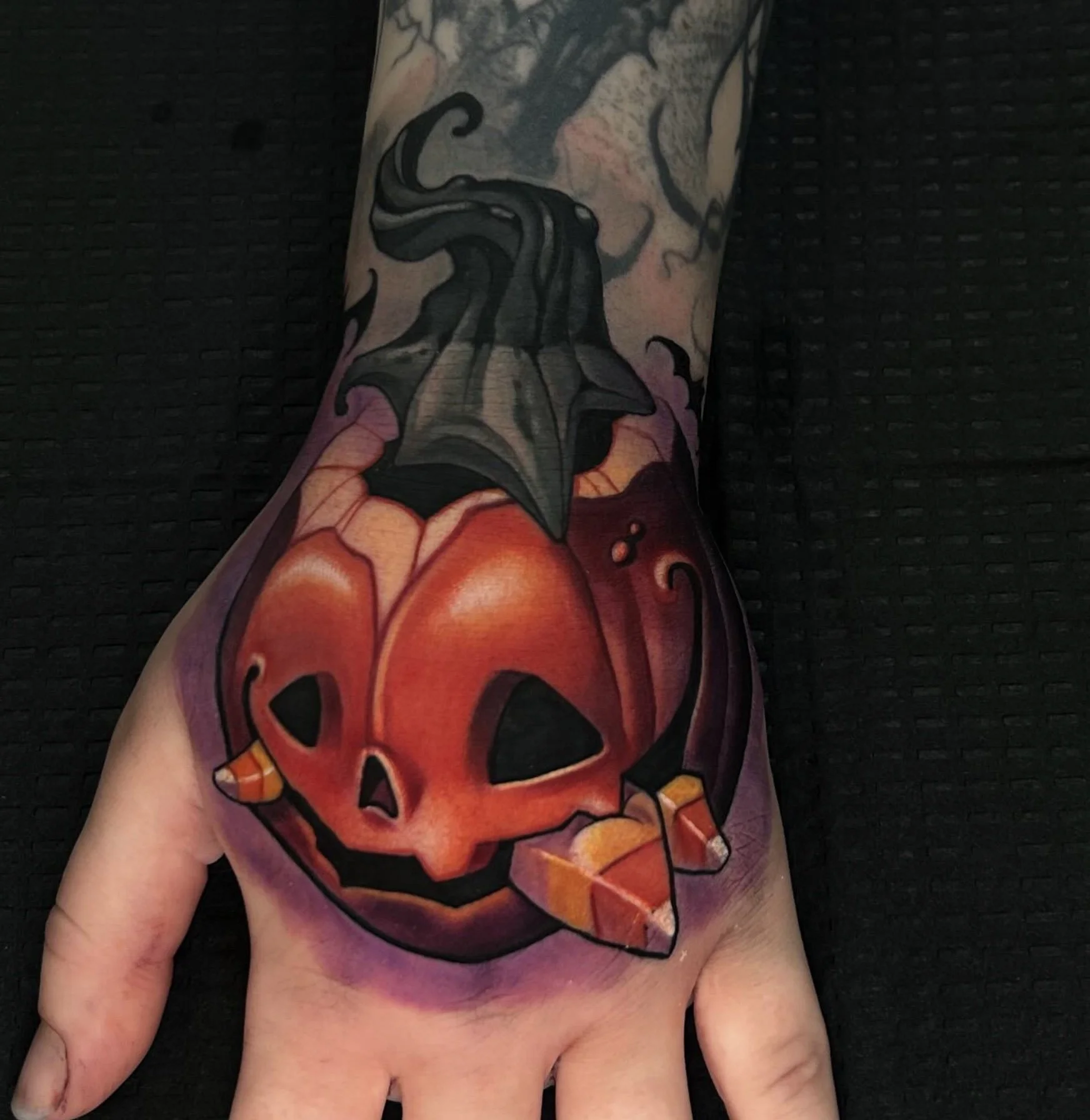 A tattoo of a skull with flames on a person's upper arm.