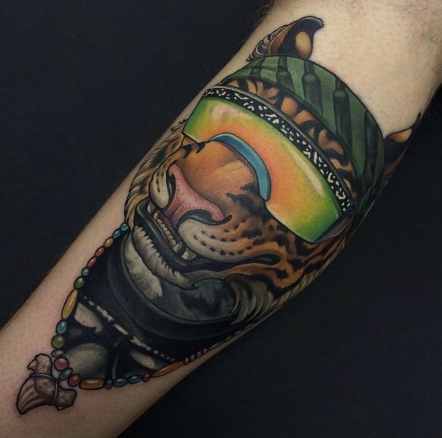 Tattoo of a tiger wearing sunglasses and a beaded necklace, with a colorful background.