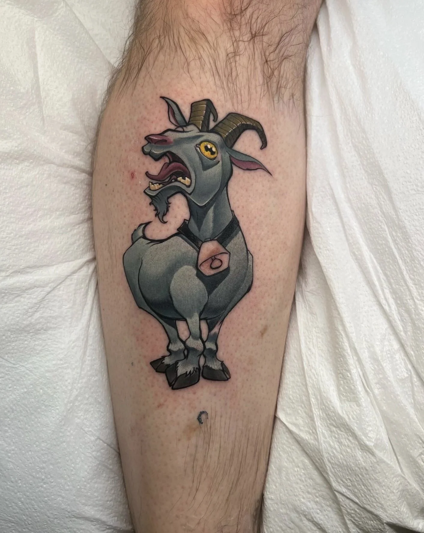 Tattoo of an angry goat with large horns on a person's upper arm.