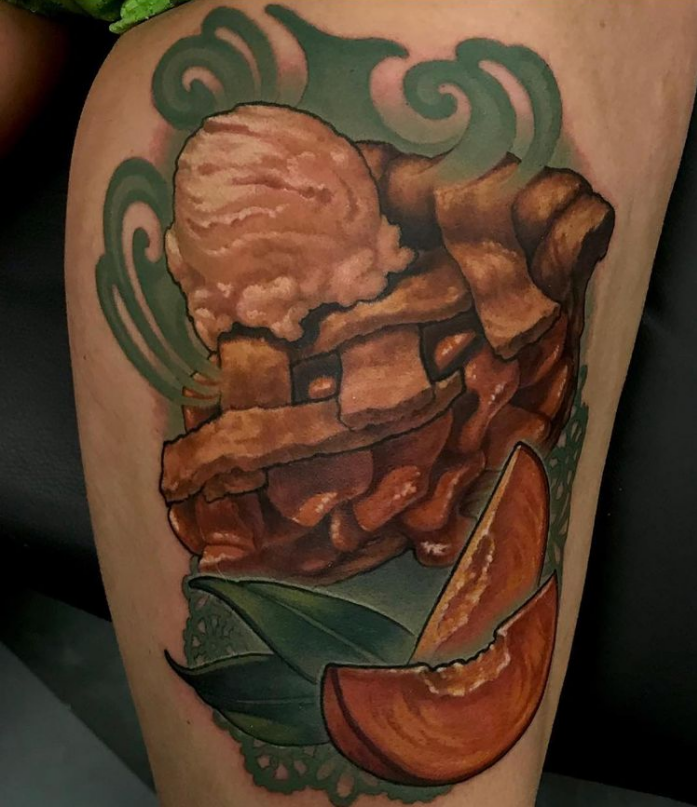 Tattoo of a dessert featuring a scoop of ice cream, pie slices, green leaves, and swirling decorative elements.