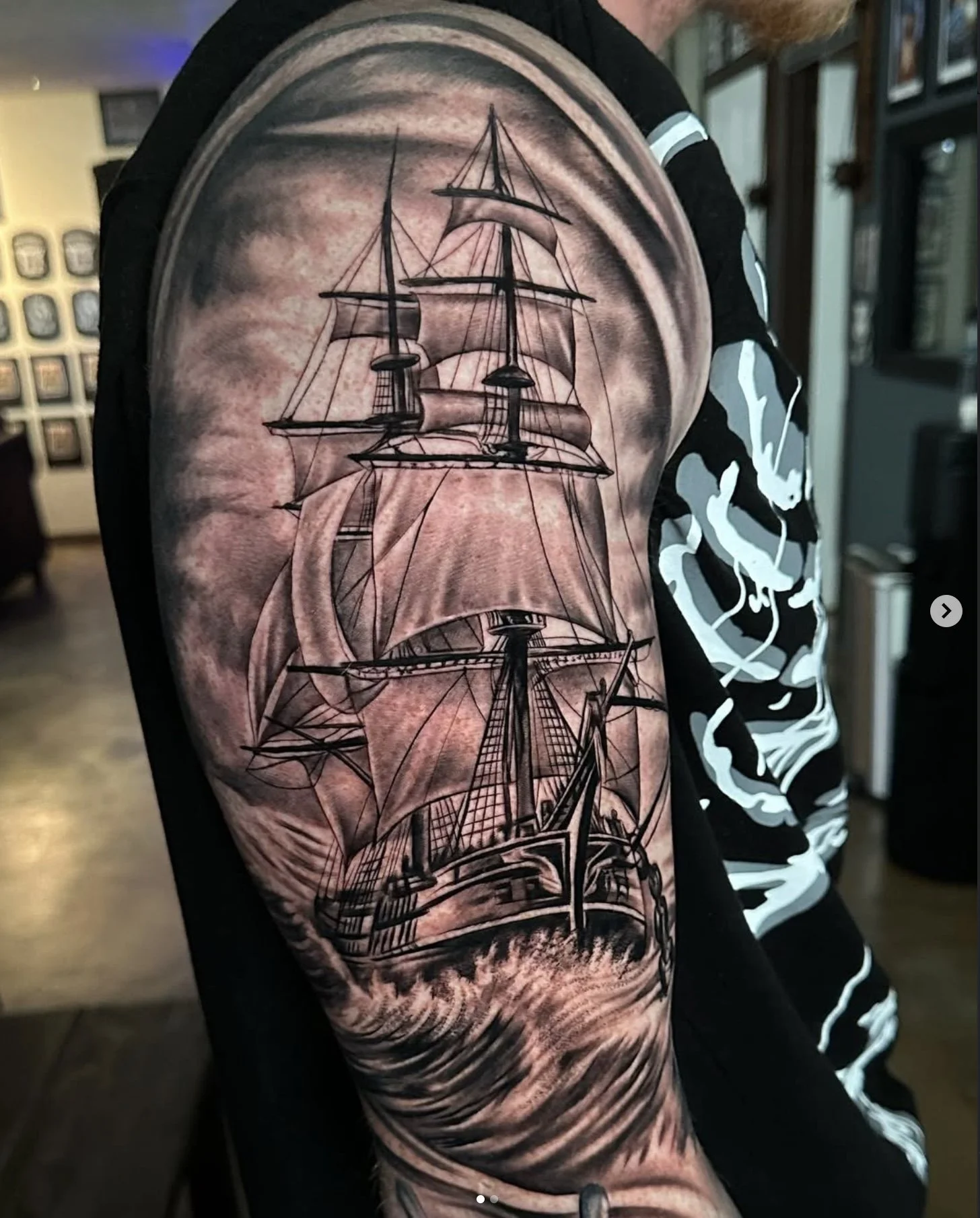 Tattoo of a detailed sailing ship on a person's upper arm.