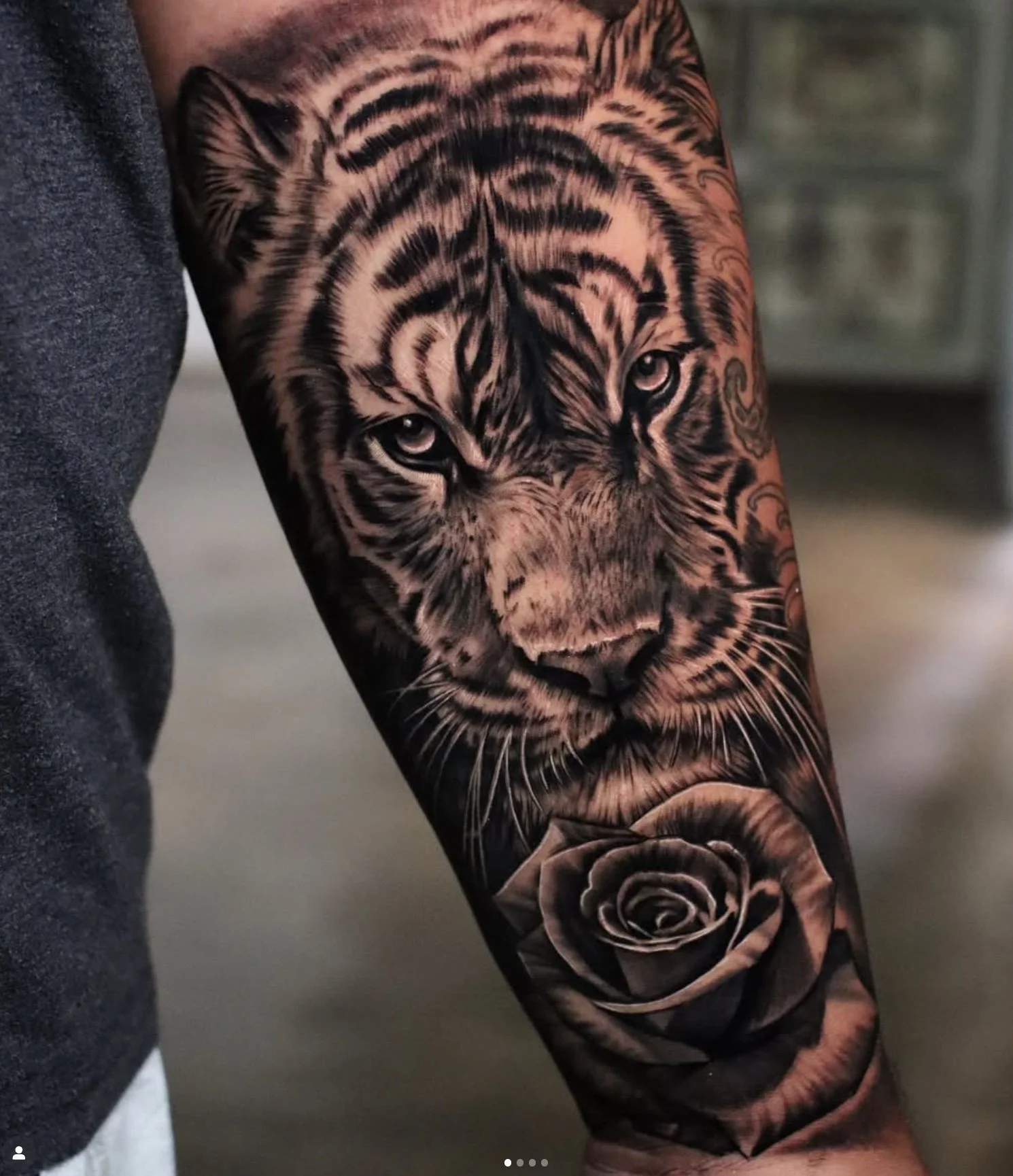 Tattoo of a tiger's face and a rose on a person's arm.