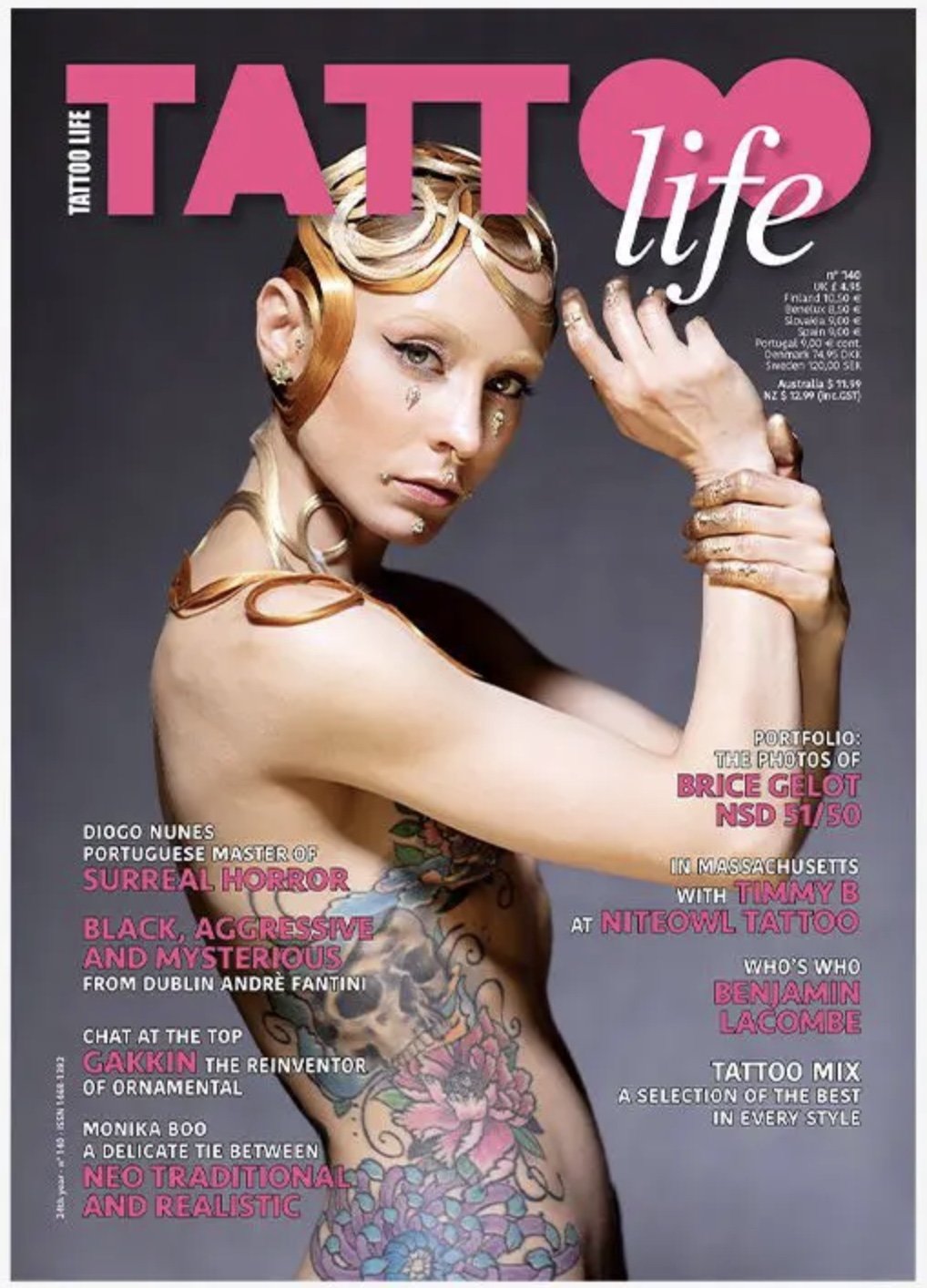 Magazine cover featuring a woman with elaborate tattoos and metallic accessories, with bold pink and white text about tattoos and tattoo artists.