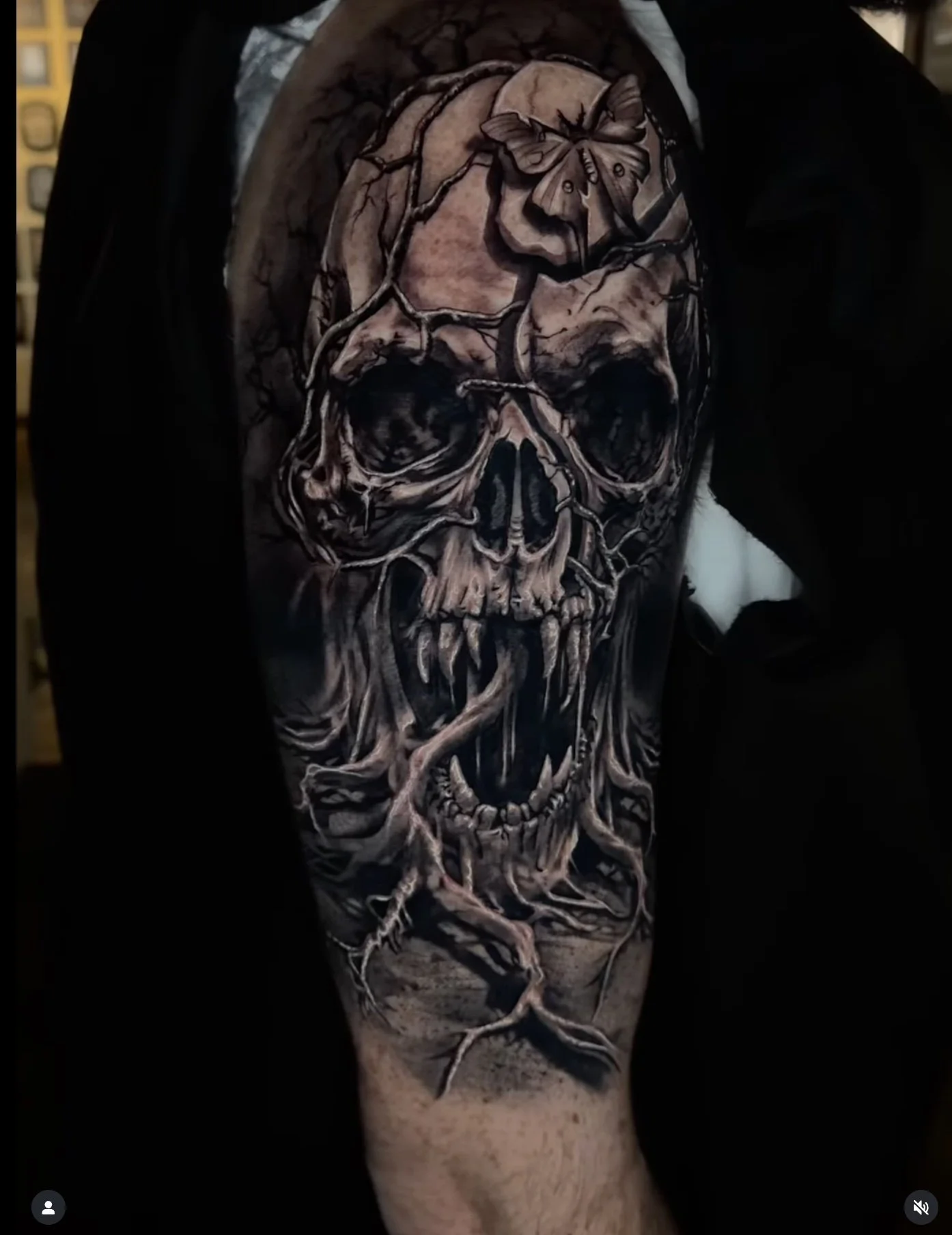 Tattoo of a skull with a tree growing through it, a butterfly on top, and roots extending down the arm.
