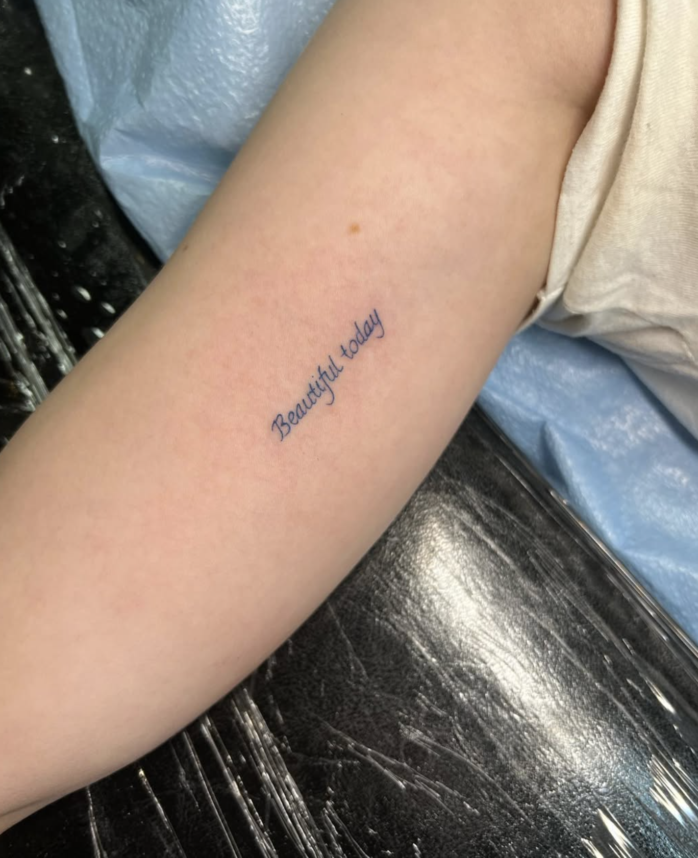 Tattoo on forearm in blue ink that reads 'Beautyful today' with slight misspelling of 'beautiful'.