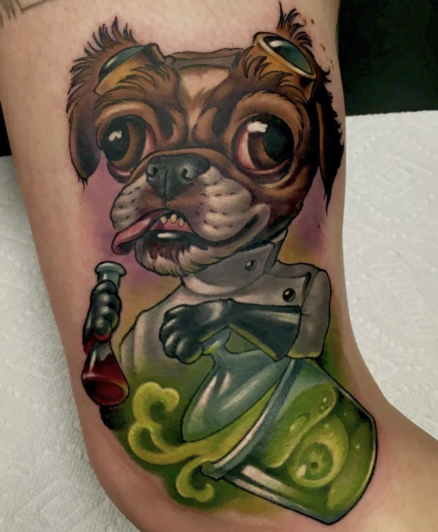 Colorful tattoo of a cartoon pug dog wearing goggles, holding a potion bottle, with vibrant accents and a lively design.