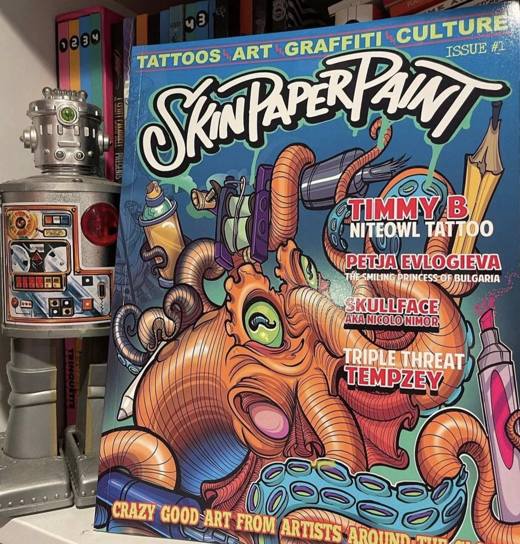 Cover of Skin Paper Paint magazine featuring colorful graffiti art with a stylized octopus with green eyes and various spray paint cans. The magazine is titled 'Tattoos, Art, Graffiti, Culture' and lists artists such as Timmy B, Petja Evligeva, Skullface, and Tempzey.