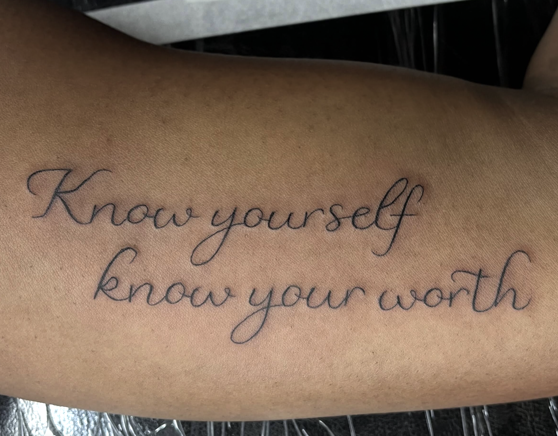 A tattoo on a person's skin with the words "Know yourself" written in cursive black ink.