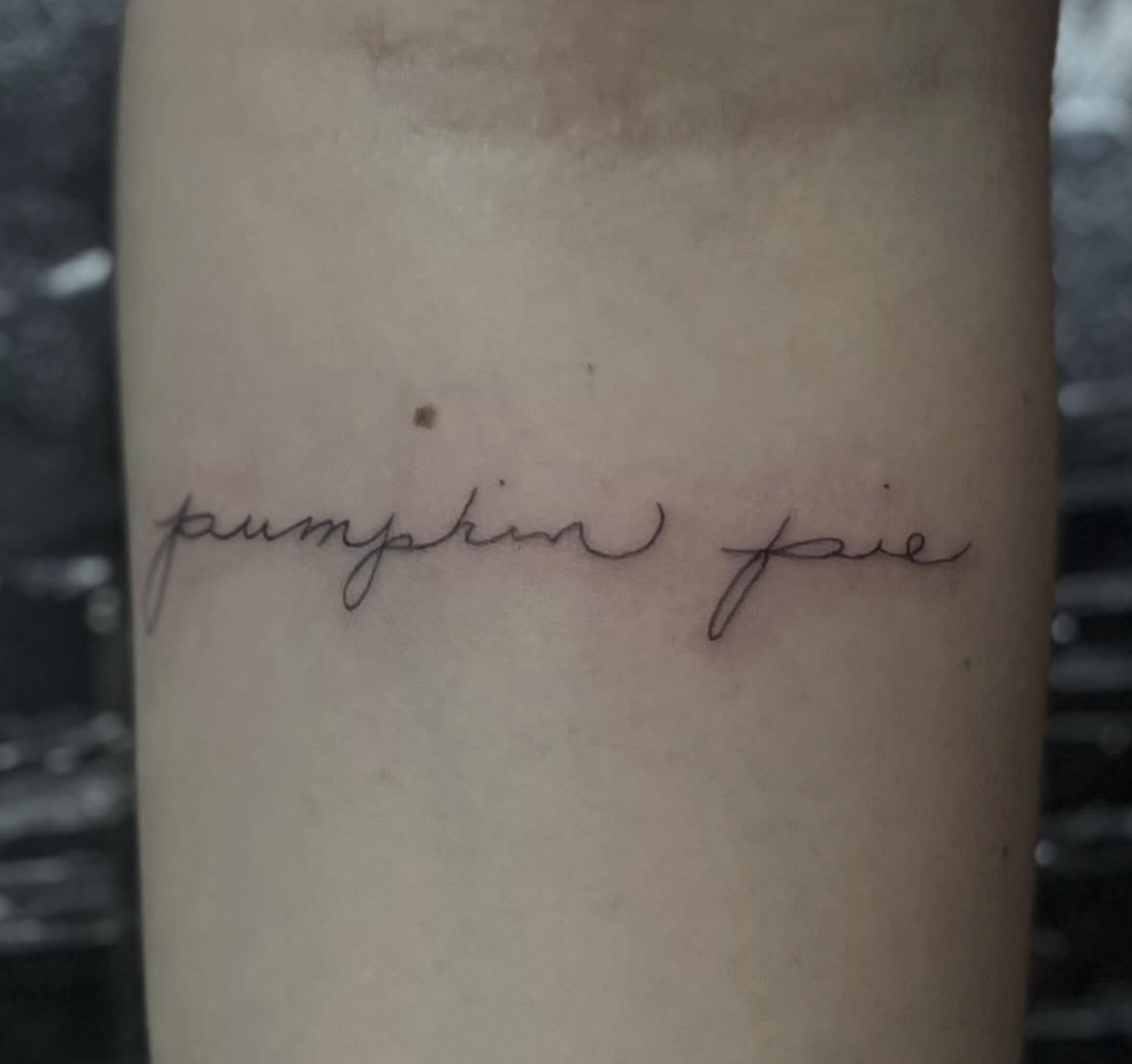 A close-up of a tattoo on skin with cursive writing that appears to say 'pumpkin joe'.