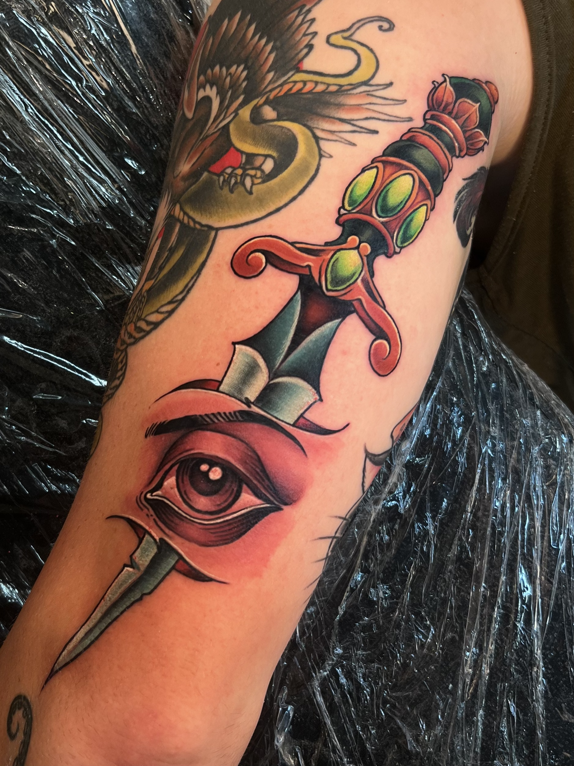 Tattoo of a dragon and a dagger on a person's arm.
