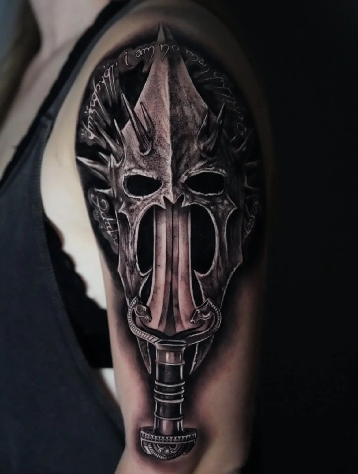 Black tattoo of a Viking-style axe with a skull face design on the arm.