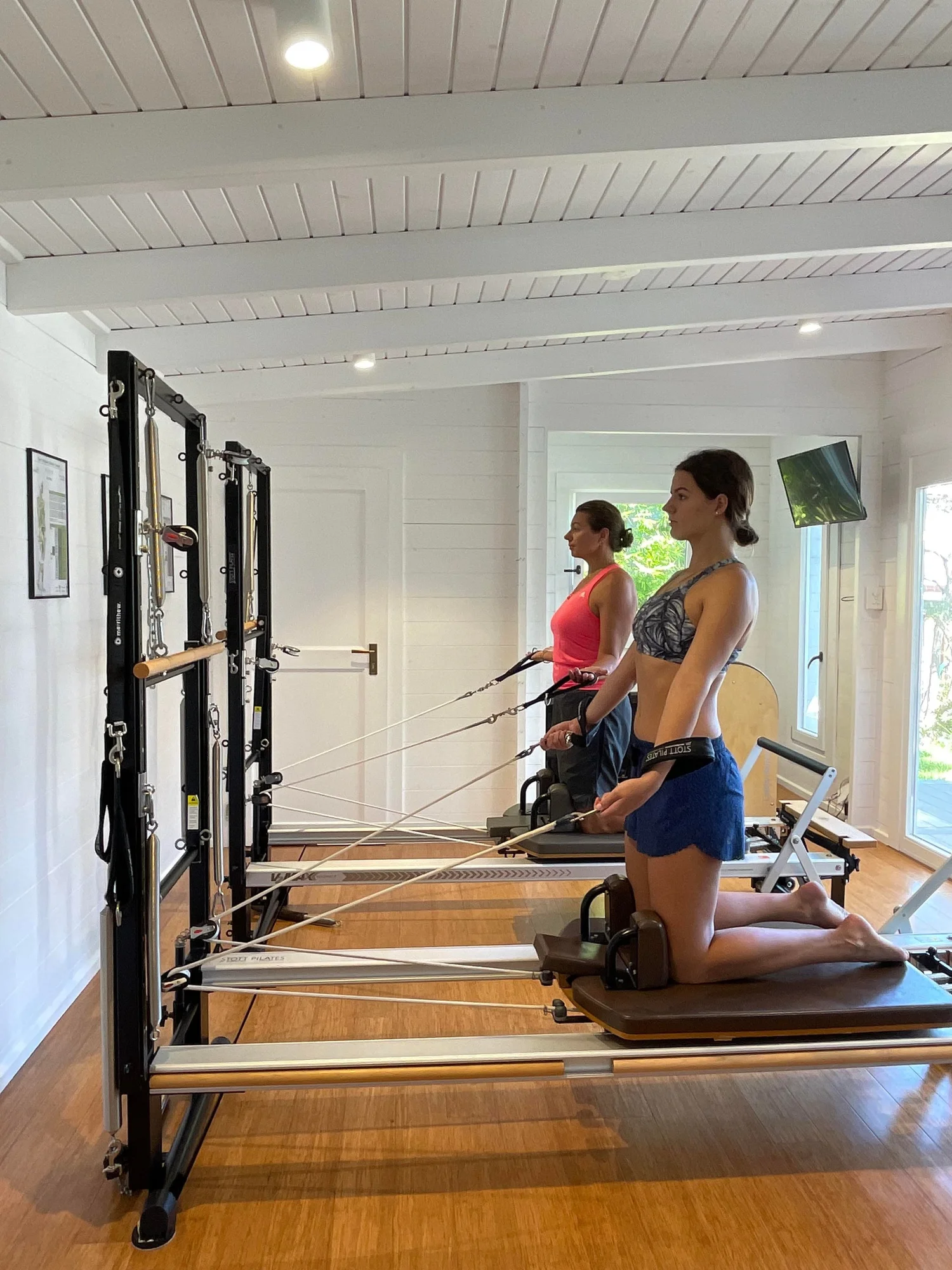 Two clients training side by side on reformers in the studio