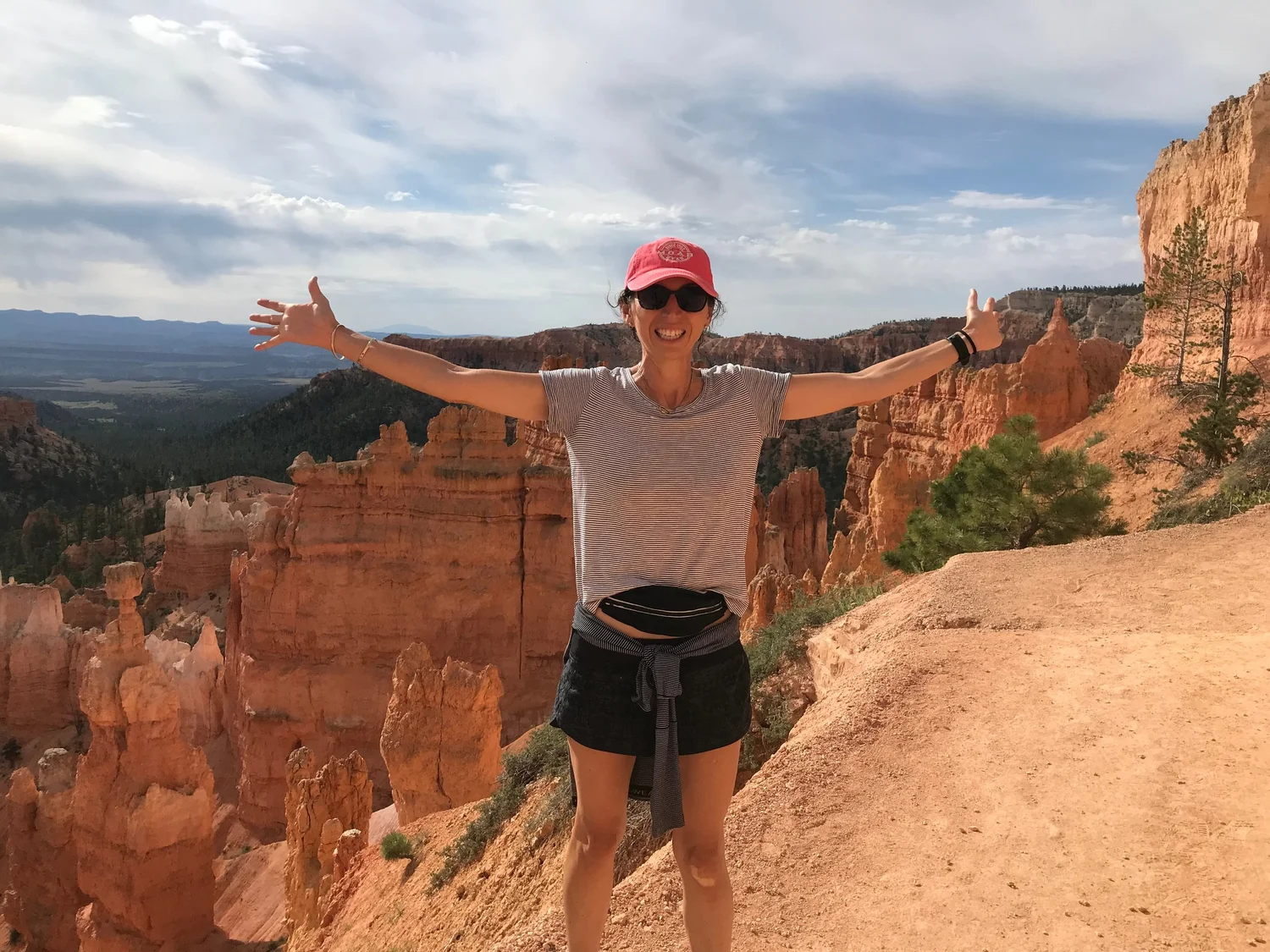 Jill, arms outstretched, on a hiking trail