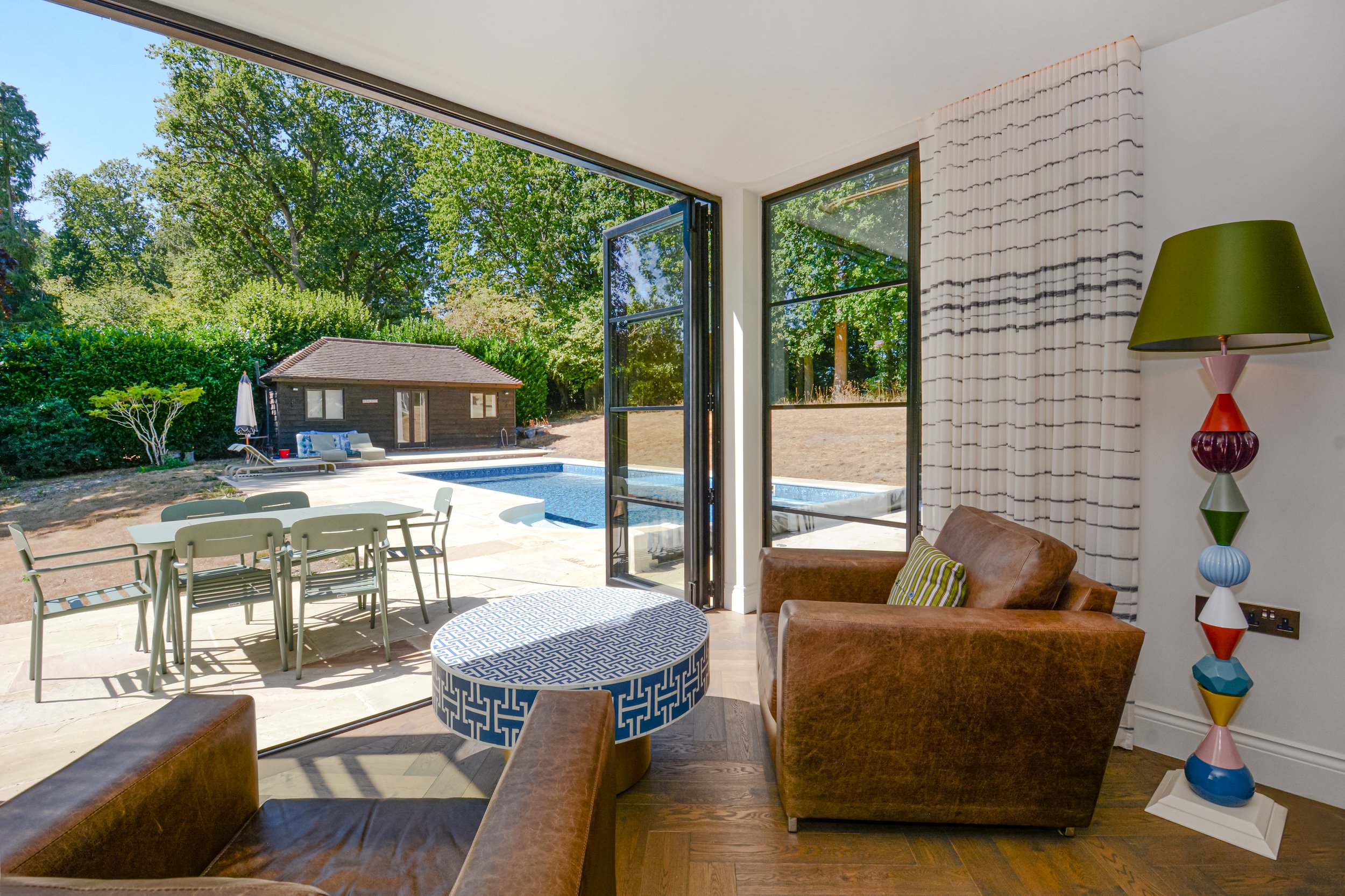 Crittal style bifold doors disappear to allow free flow between the kitchen diner and the pool