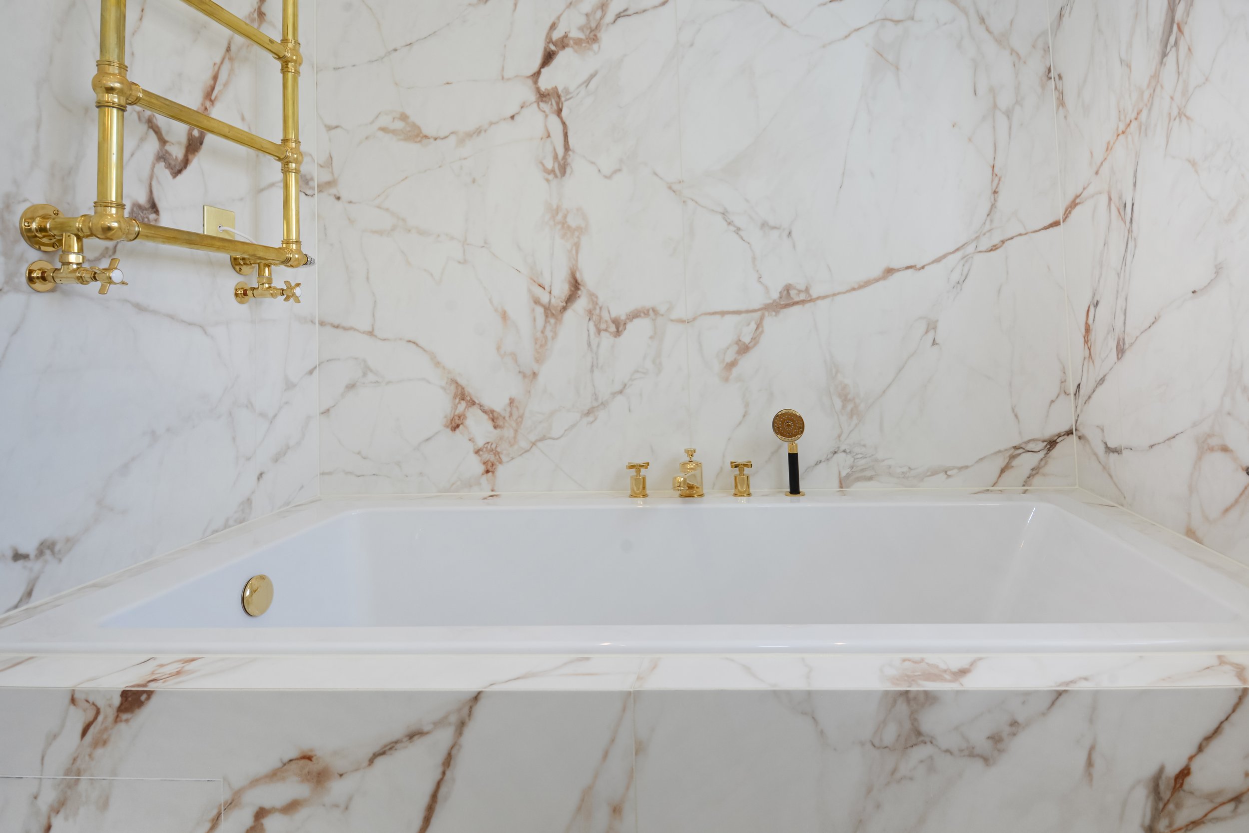 Marble effect porcelain slabs have veining that runs continuously around the bath giving the illusion of a single marble slab