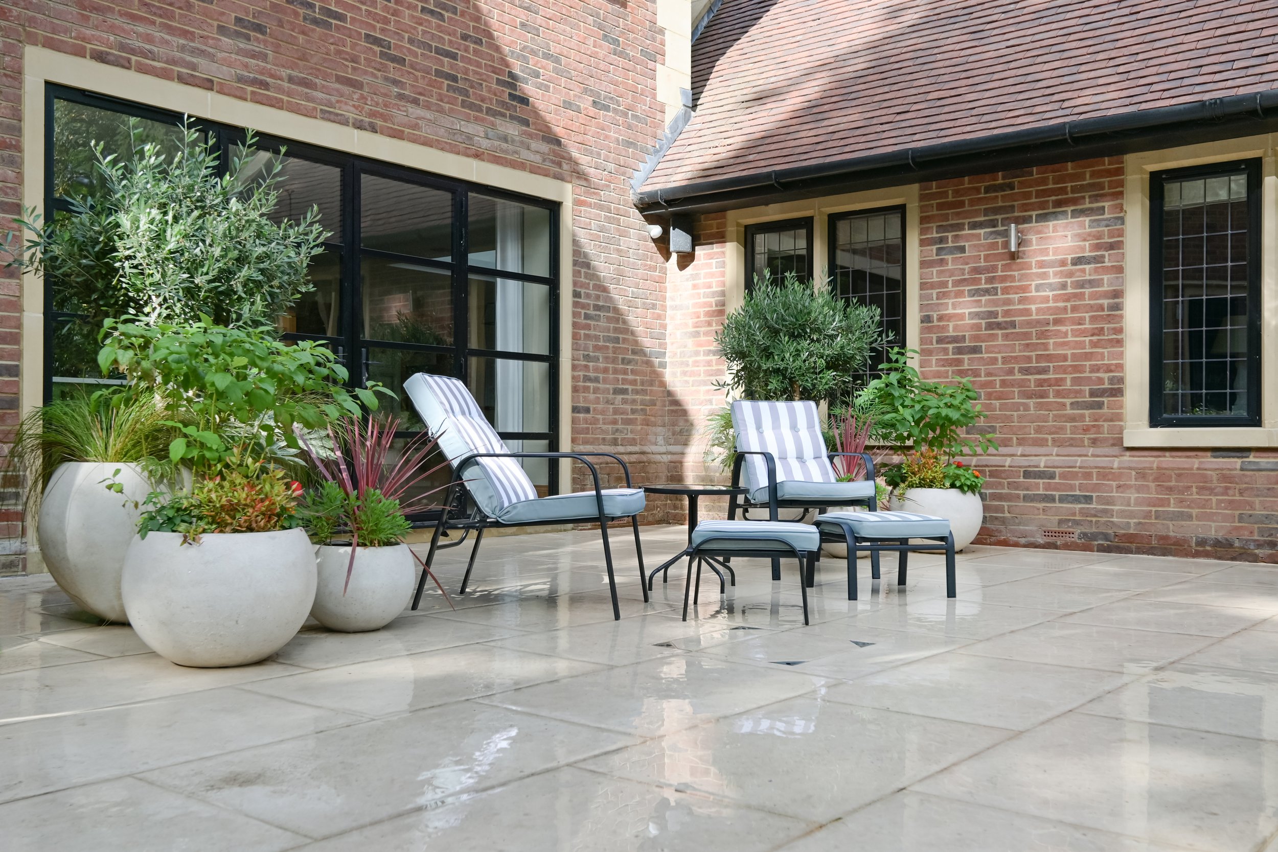 12 large pots along the patio allow us to swap the plants and add seasonal colour