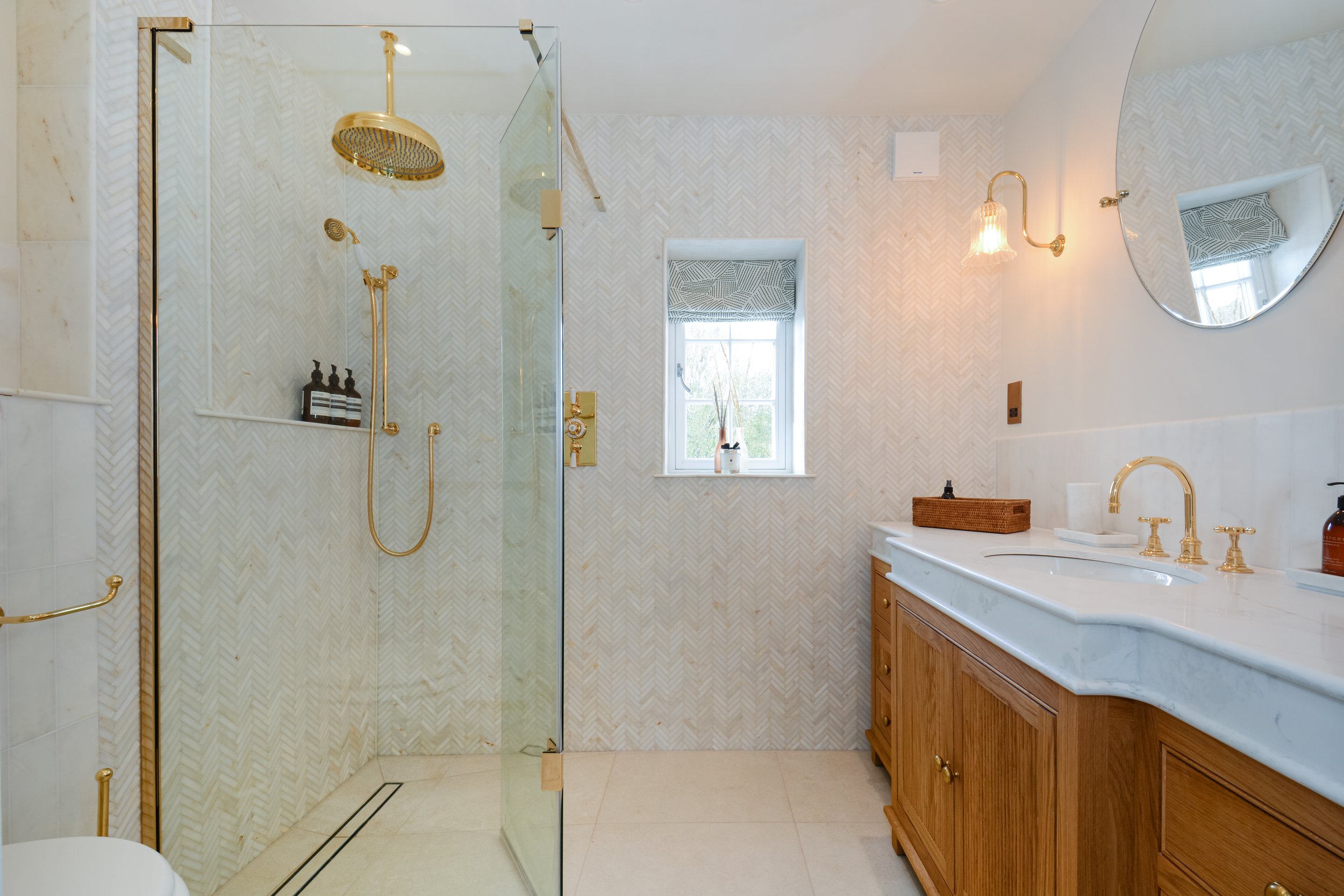 The wall of marble herringbone is the focus point of this master en suite
