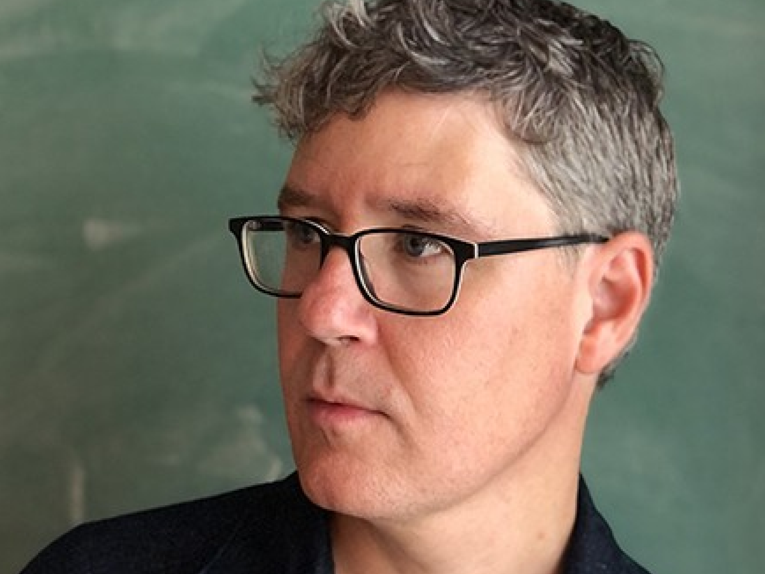 man with glasses looking over shoulder