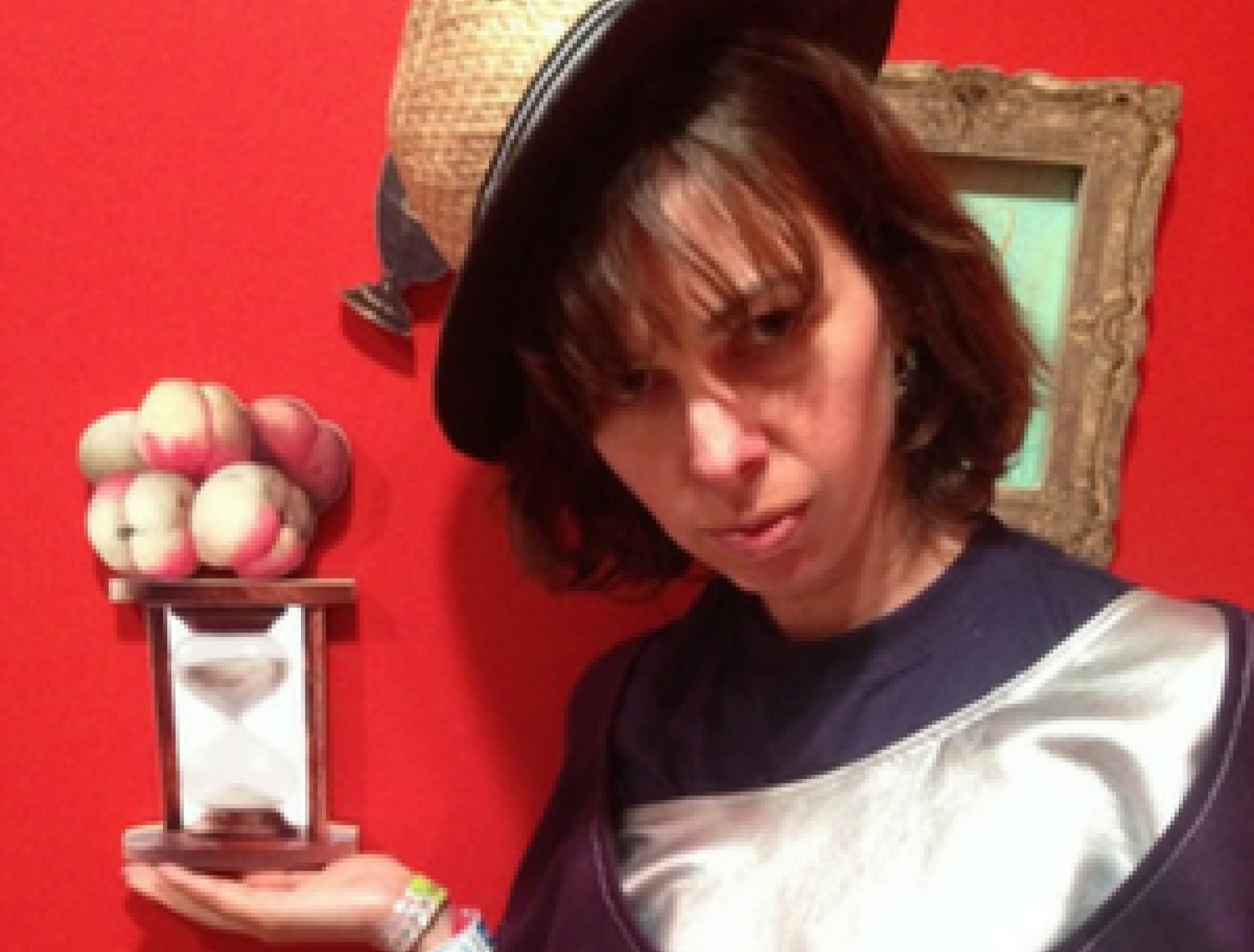 person with hat holding hourglass with peaches on top