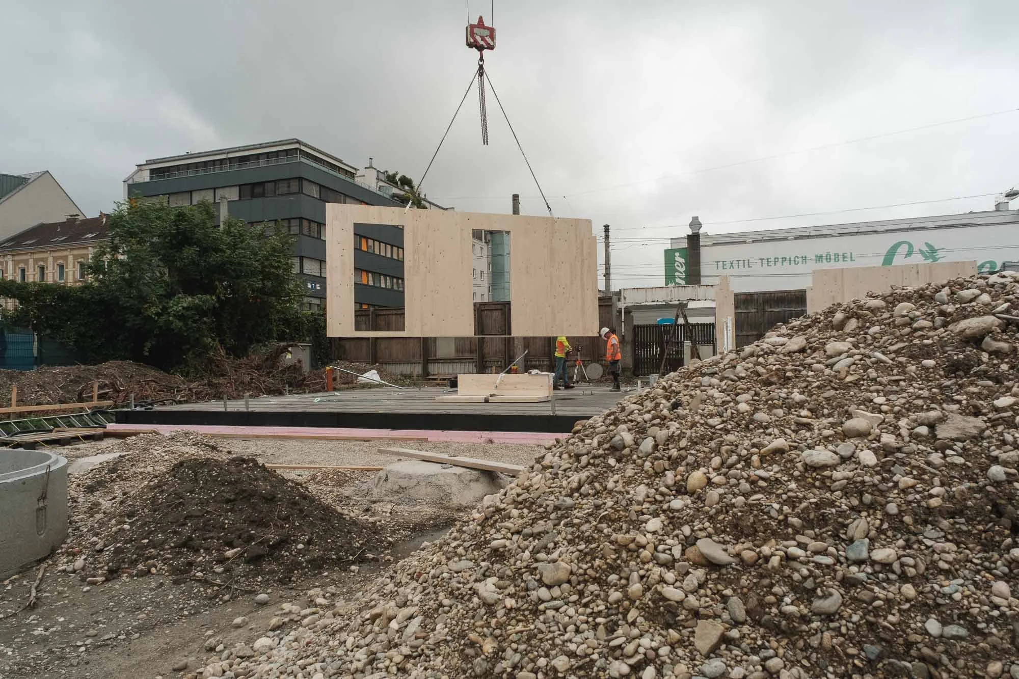 Content für Handwerksbetriebe: Kran hebt Holzmodul auf Baustelle, Linz