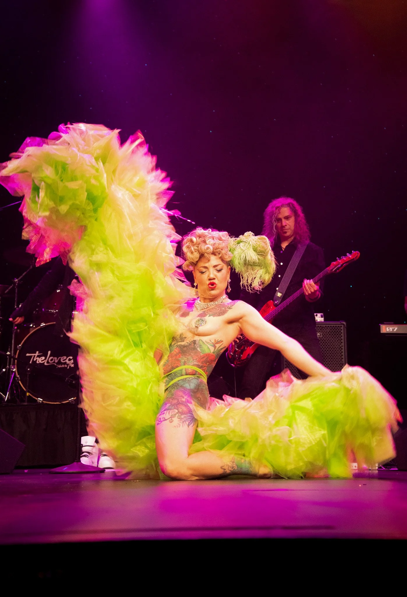 Woman on stage with a live band and a giant green boa