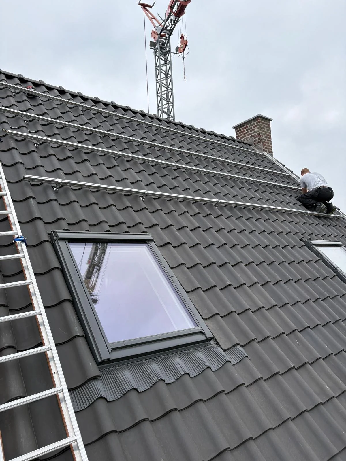 Monteur op pannendak tijdens montage van montagerails voor zonnepanelen.