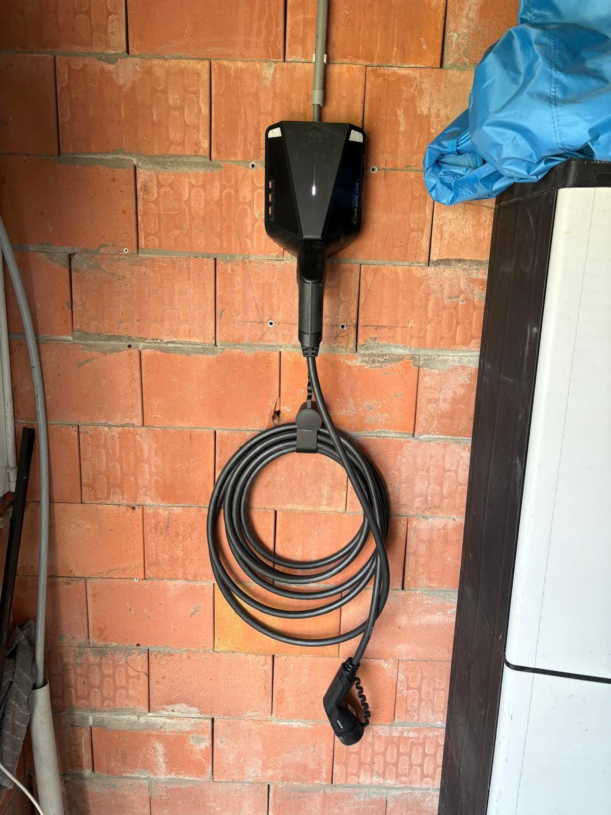 Easee-laadpaal met laadkabel aan de muur, slim aangestuurd door het Flexio-energiemanagementsysteem.