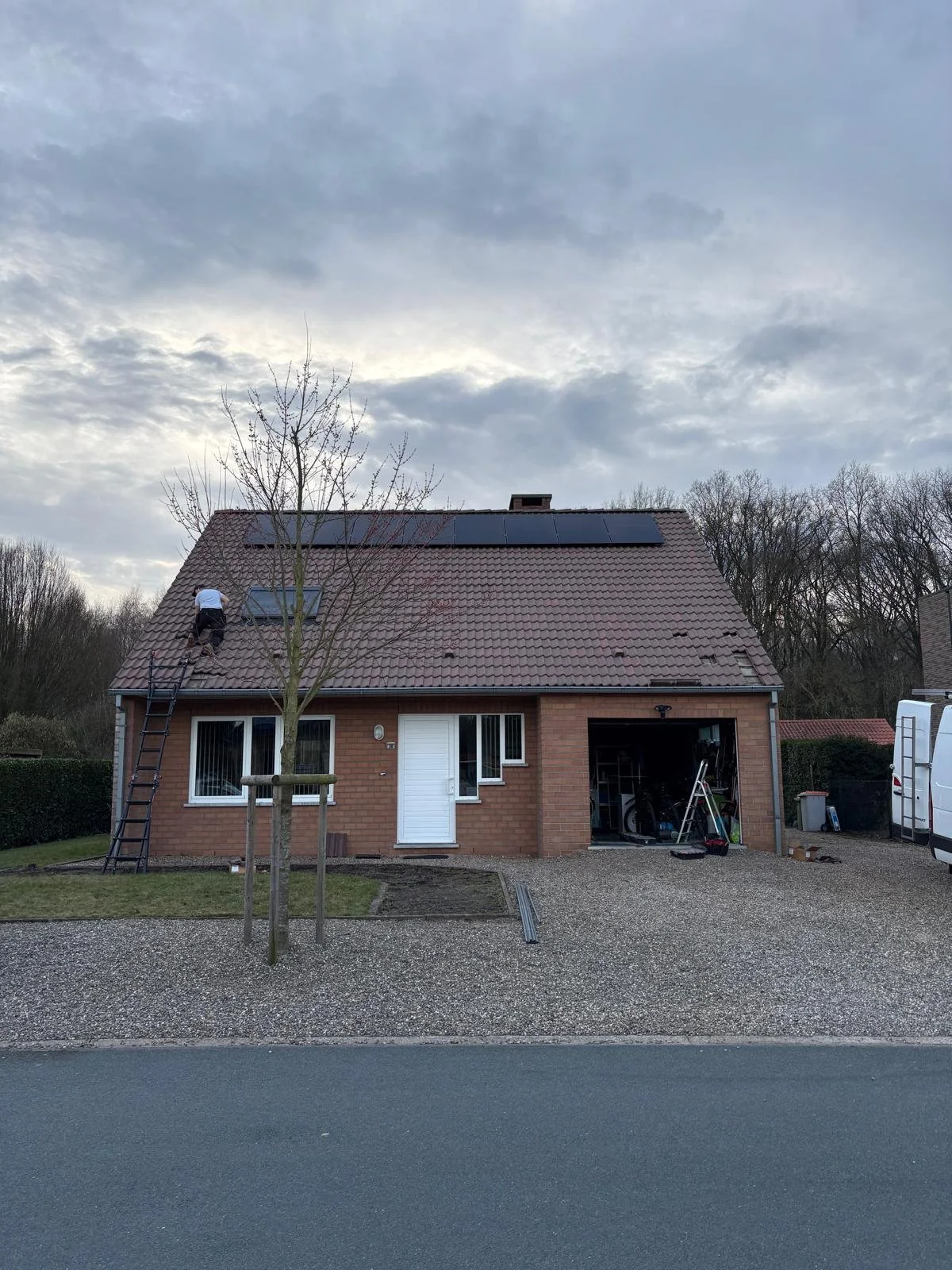 Full black zonnepanelen op pannendak in Dilsen-Stokkem met monteur tijdens de installatie.