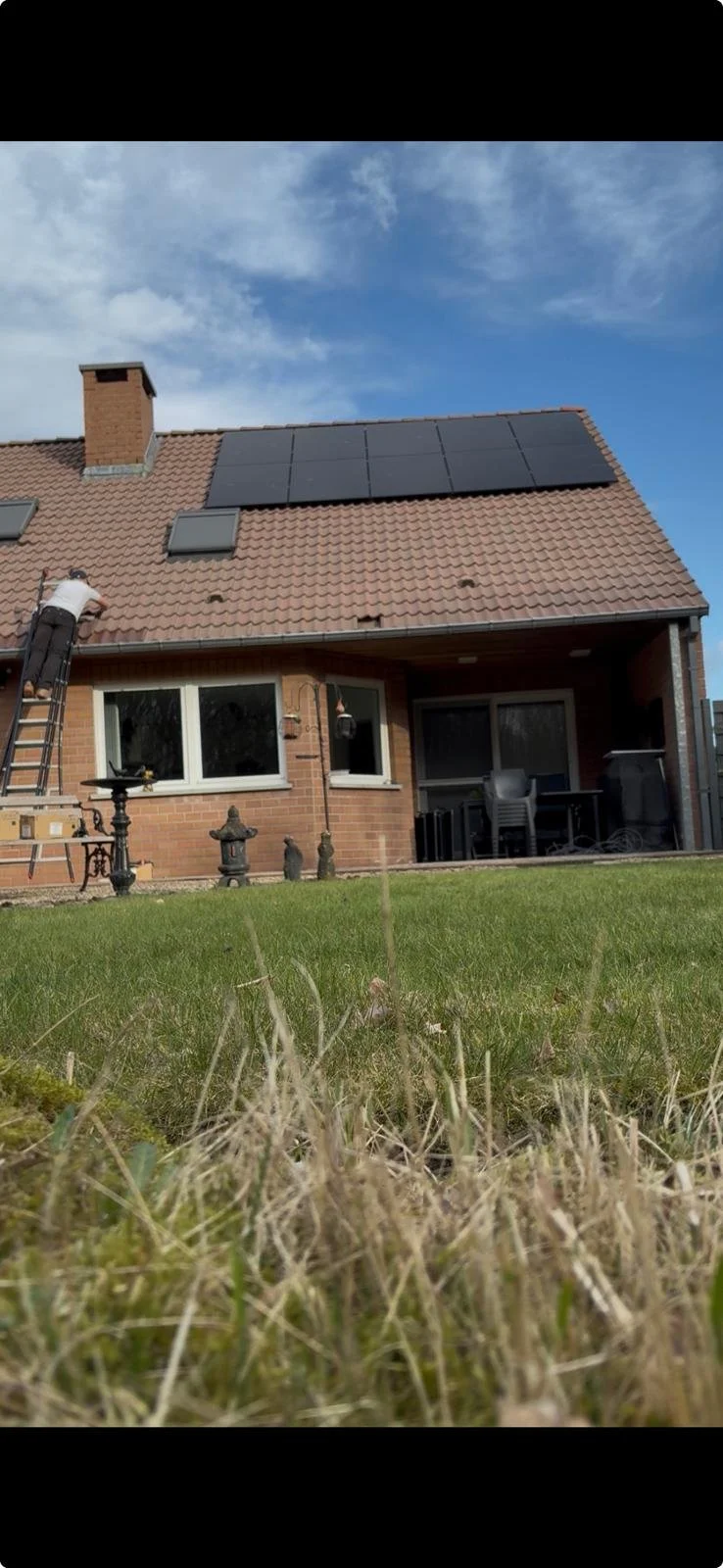 Full black zonnepanelen op pannendak in Dilsen-Stokkem met monteur tijdens de installatie.