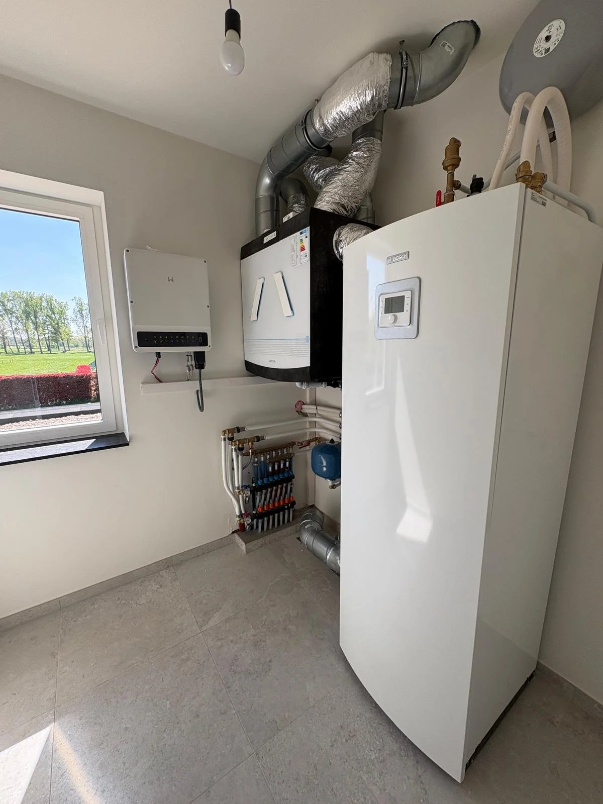 Omvormer van zonnepanelen gemonteerd tegen muur en aangesloten aan binneninstallatie
