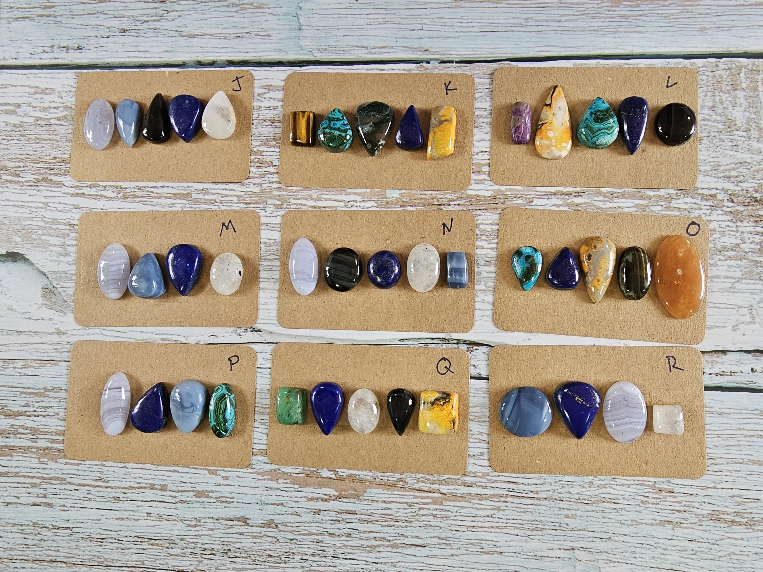 Mixed cabochon parcels laid out on whitewashed wood surface.