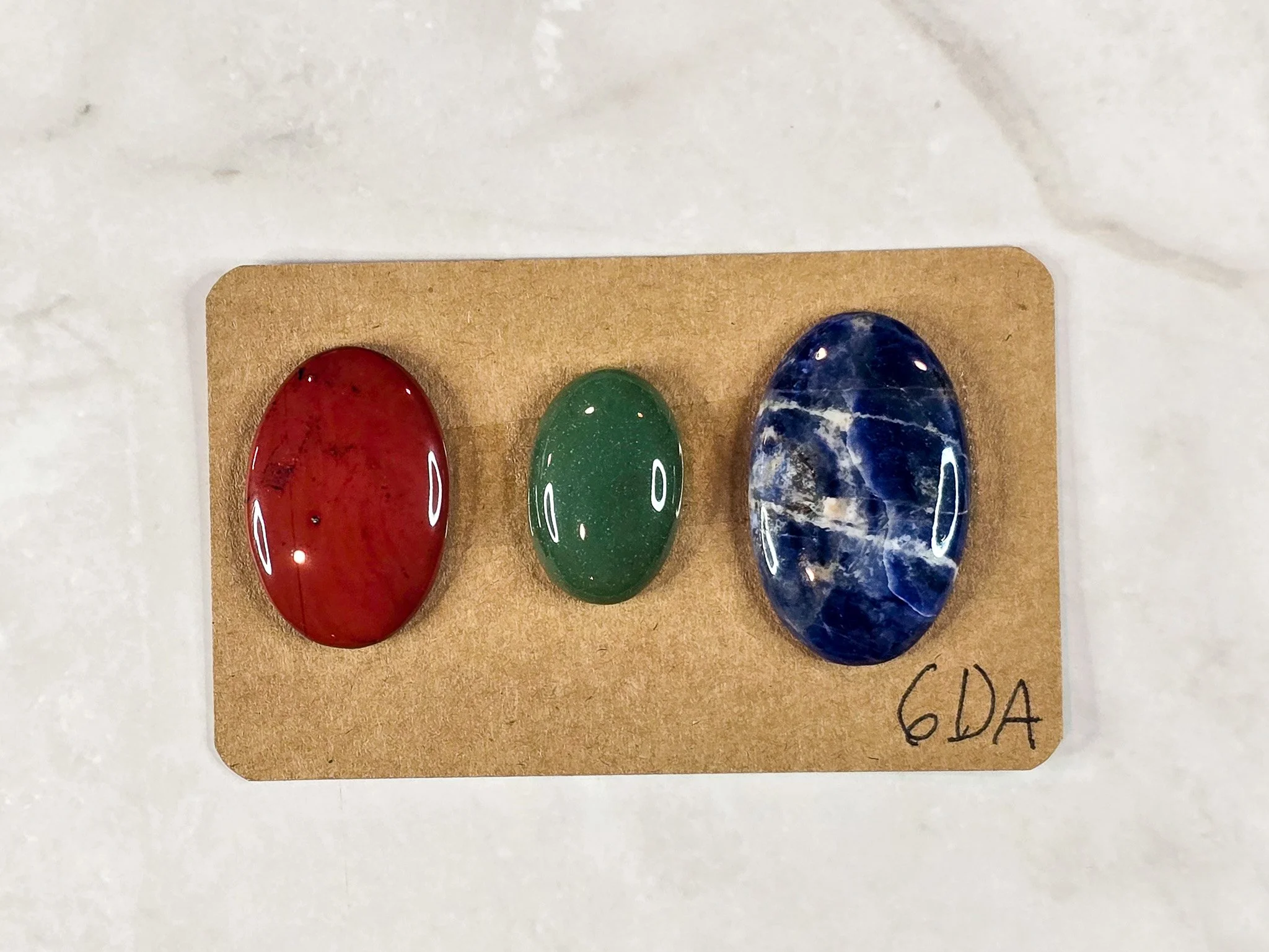 Mixed cabochon parcel including green aventurine, sodalite, and red jasper.