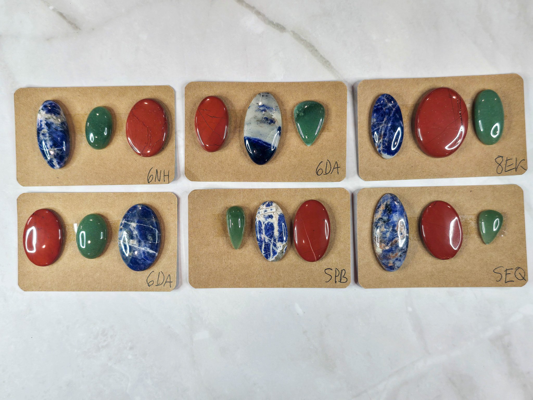 Mixed cabochon parcels including green aventurine, sodalite, and red jasper.
