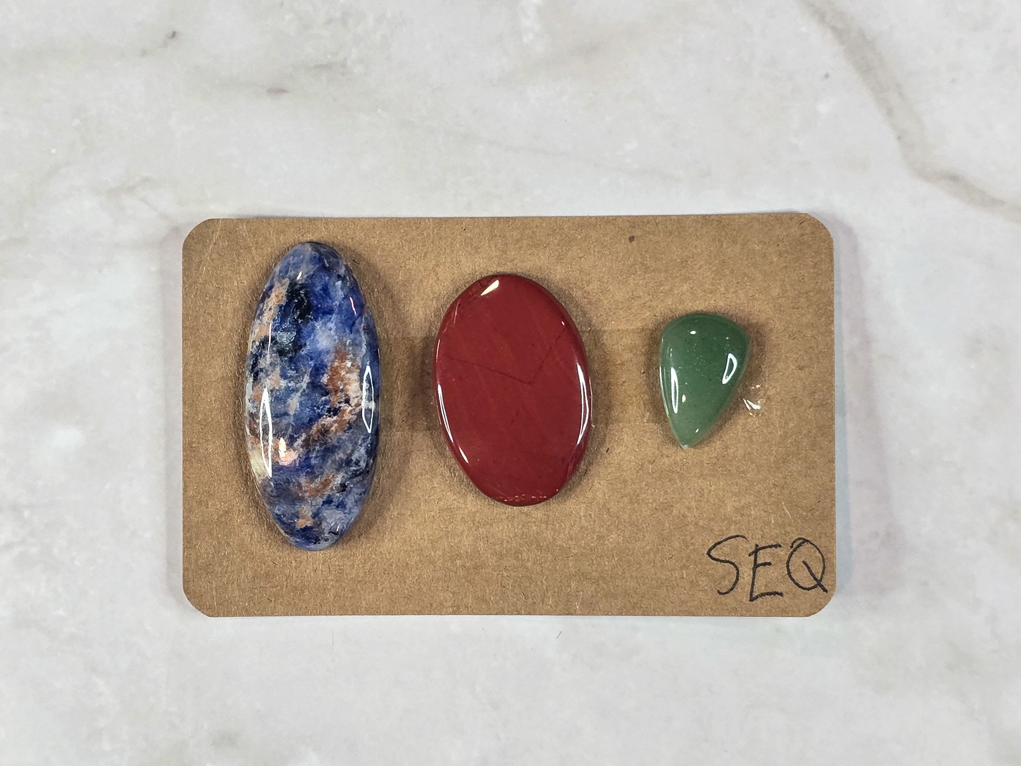 Mixed cabochon parcel including green aventurine, sodalite, and red jasper.