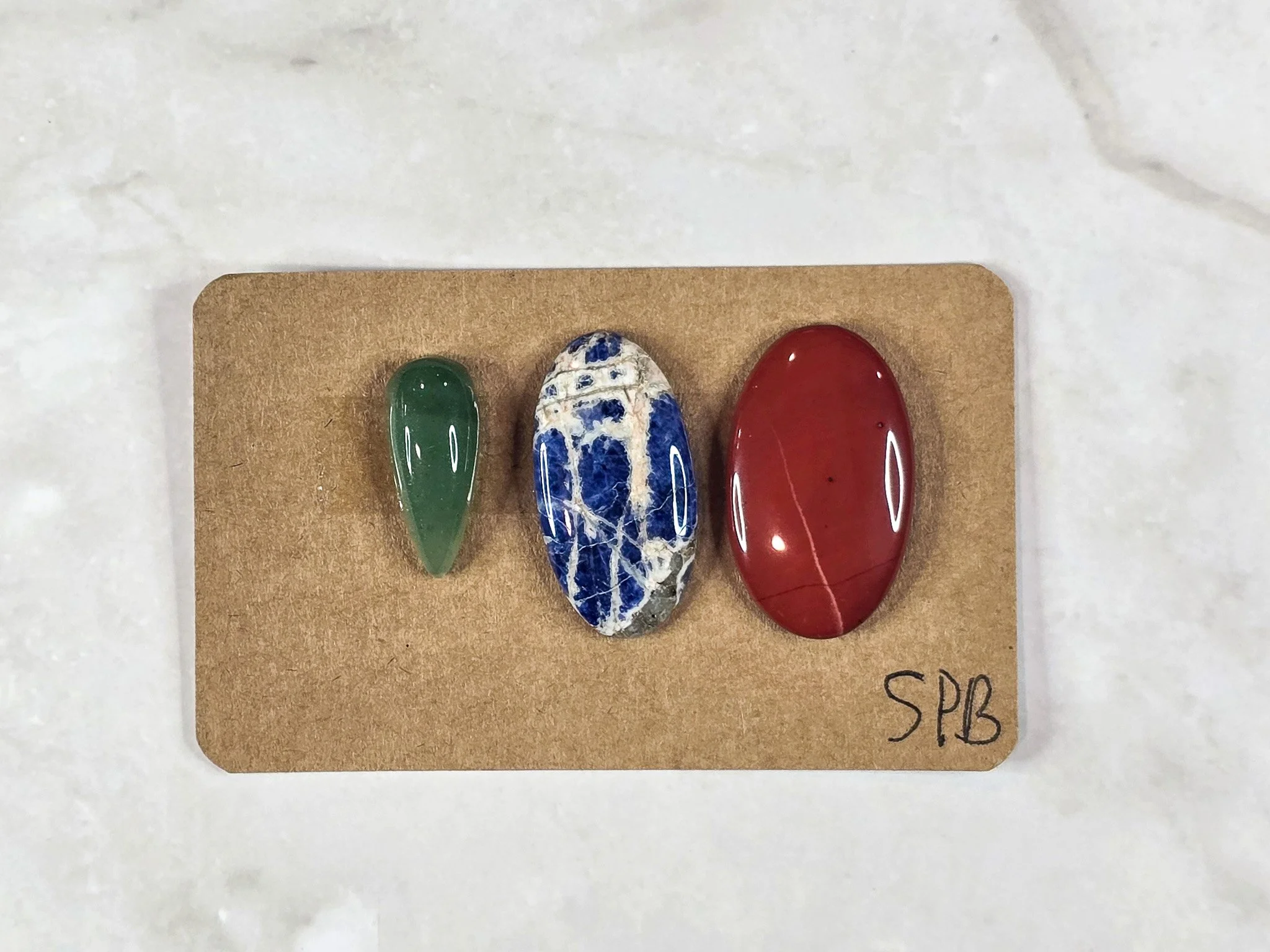 Mixed cabochon parcel including green aventurine, sodalite, and red jasper.