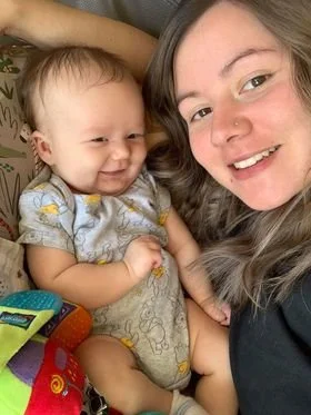 Picture of a mother smiling beside her newborn baby.