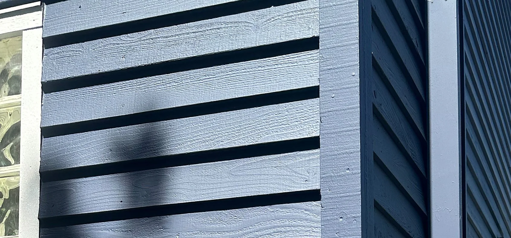 Close-up of a modern building exterior featuring horizontally arranged wooden siding and a vertical metal siding section.