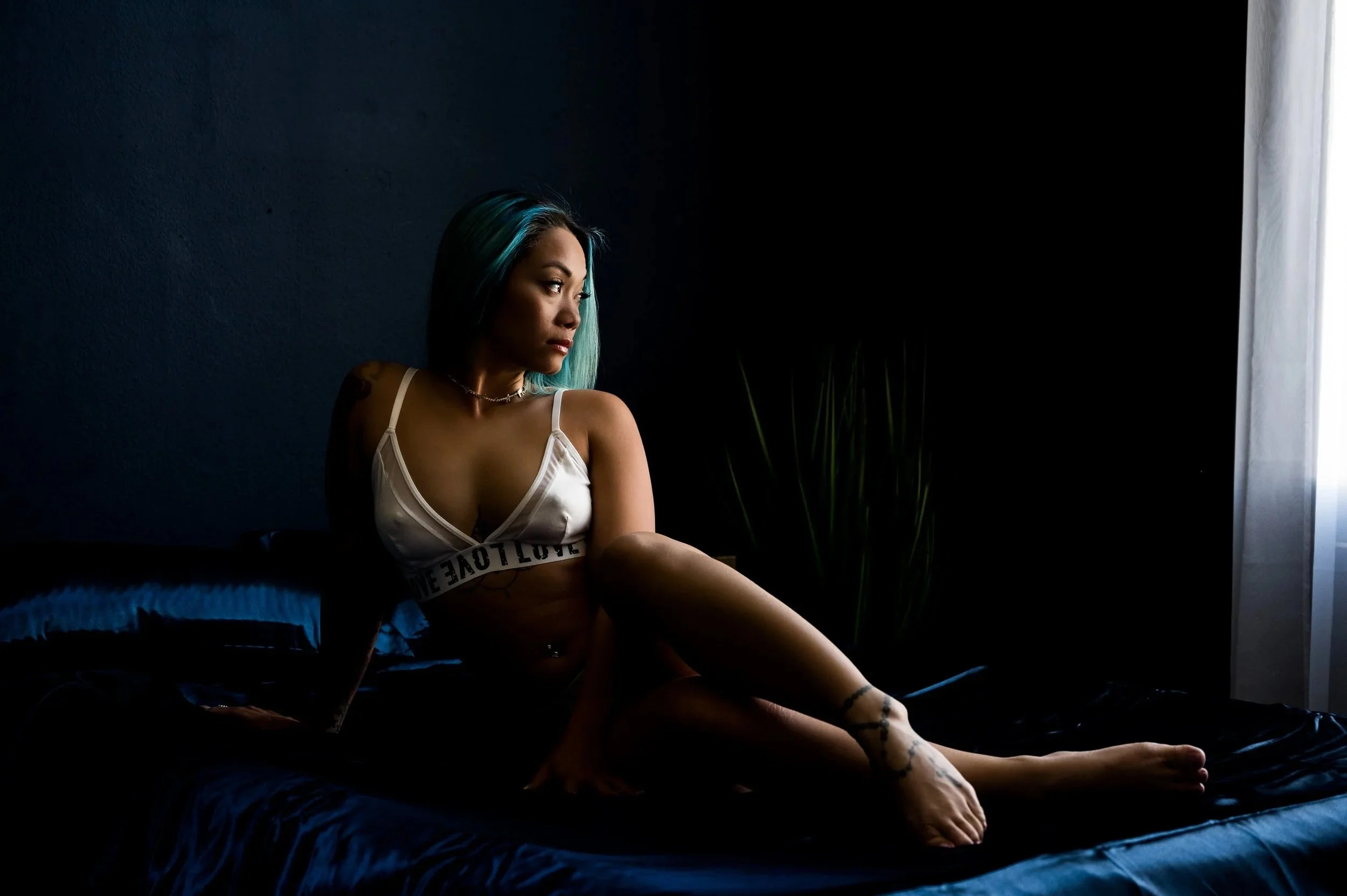 Moody boudoir photography Los Angeles woman posed on bed blue room Black Kat Studios