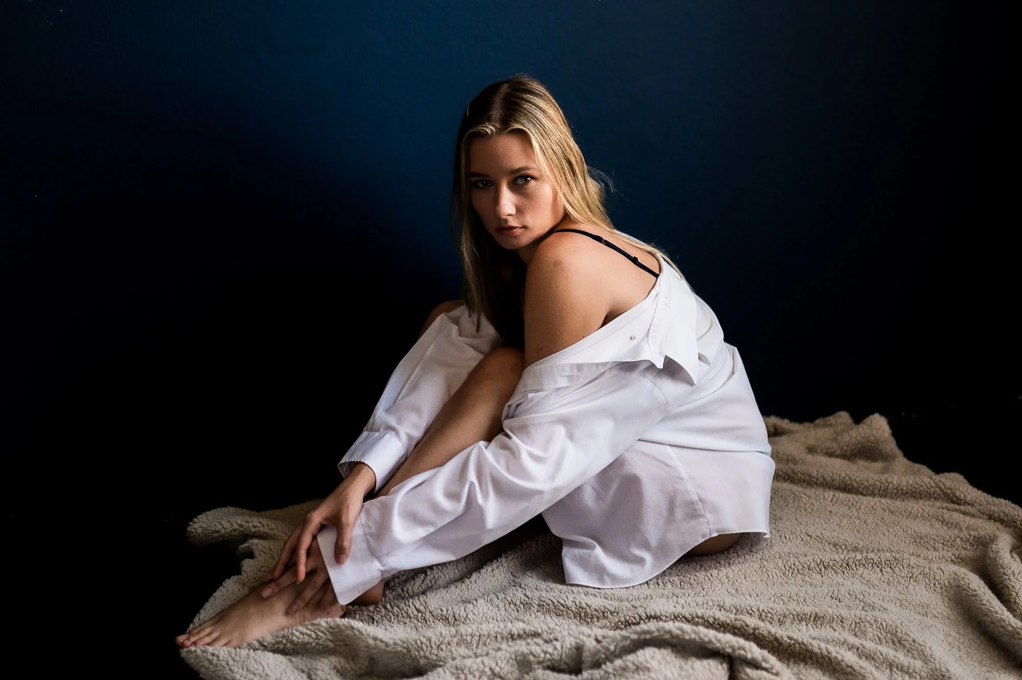 Woman posing on the floor in a white shirt during a boudoir session at Black Kat Studios in Los Angeles