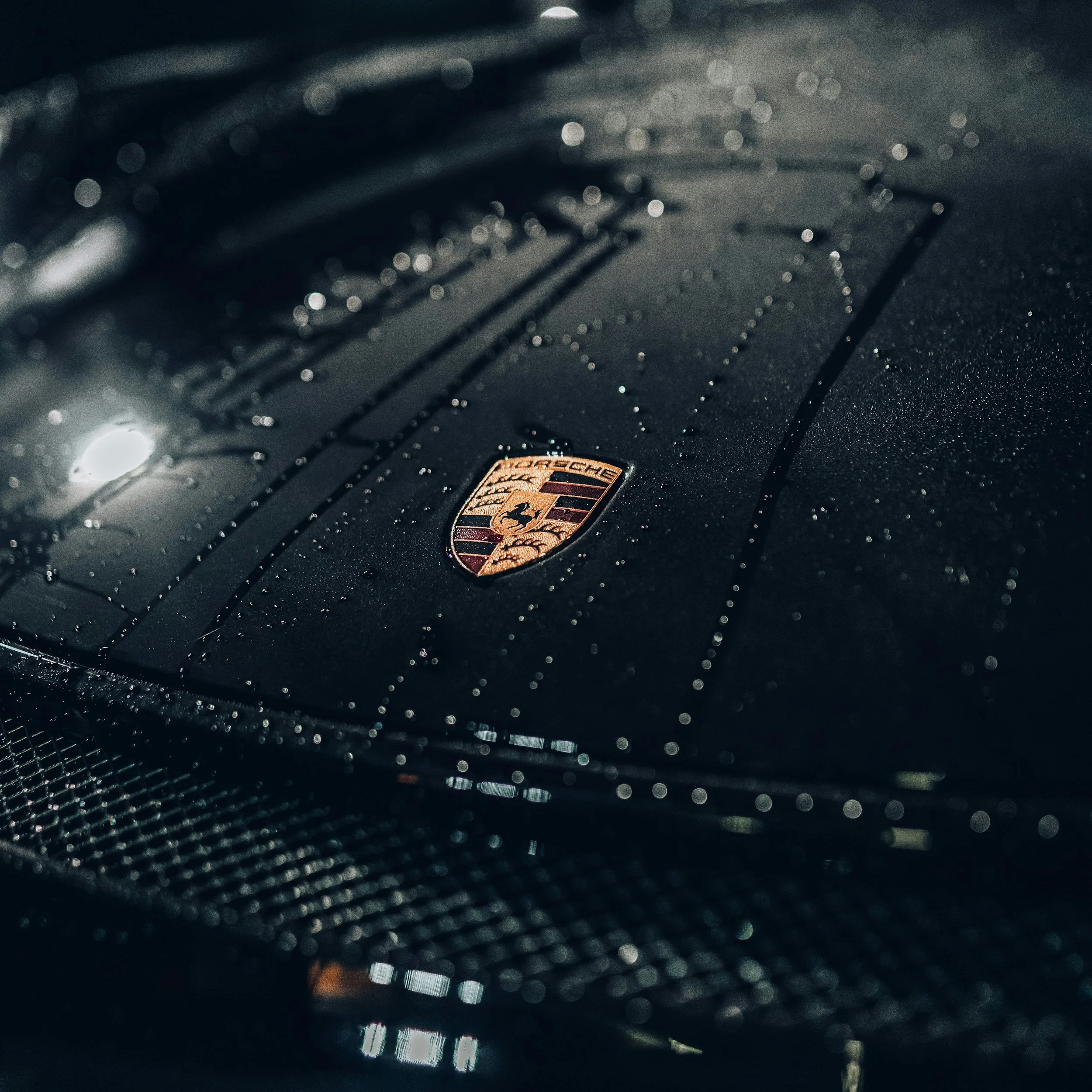 Water beading on a dark Porsche hood protected with ceramic coating.