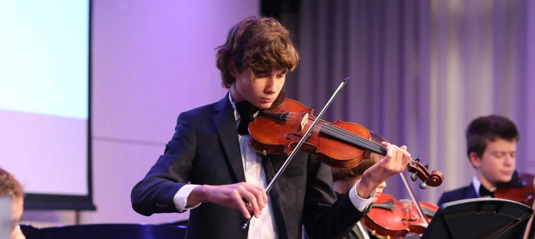 Boy performing violin for music scholarship.
