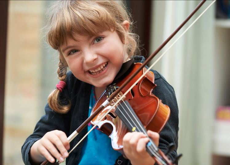 A young girl smiling during her music lesson.