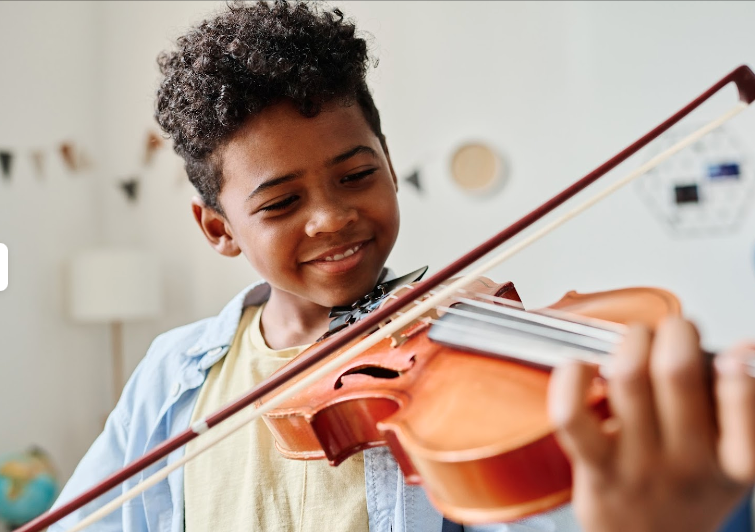 A boy practicing his violin technique looking happy.