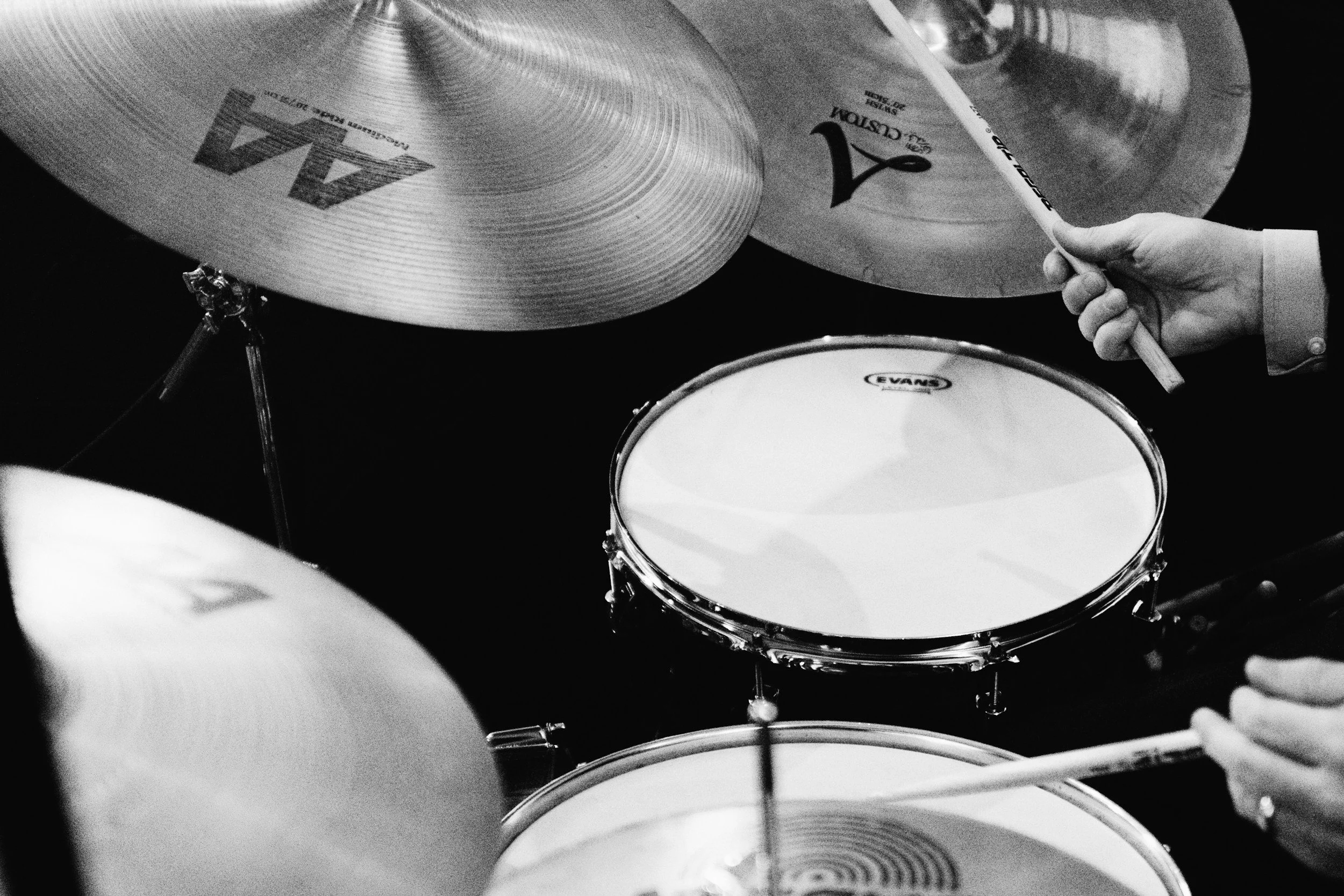 Drummer playing drum kit with drum sticks during lesson.