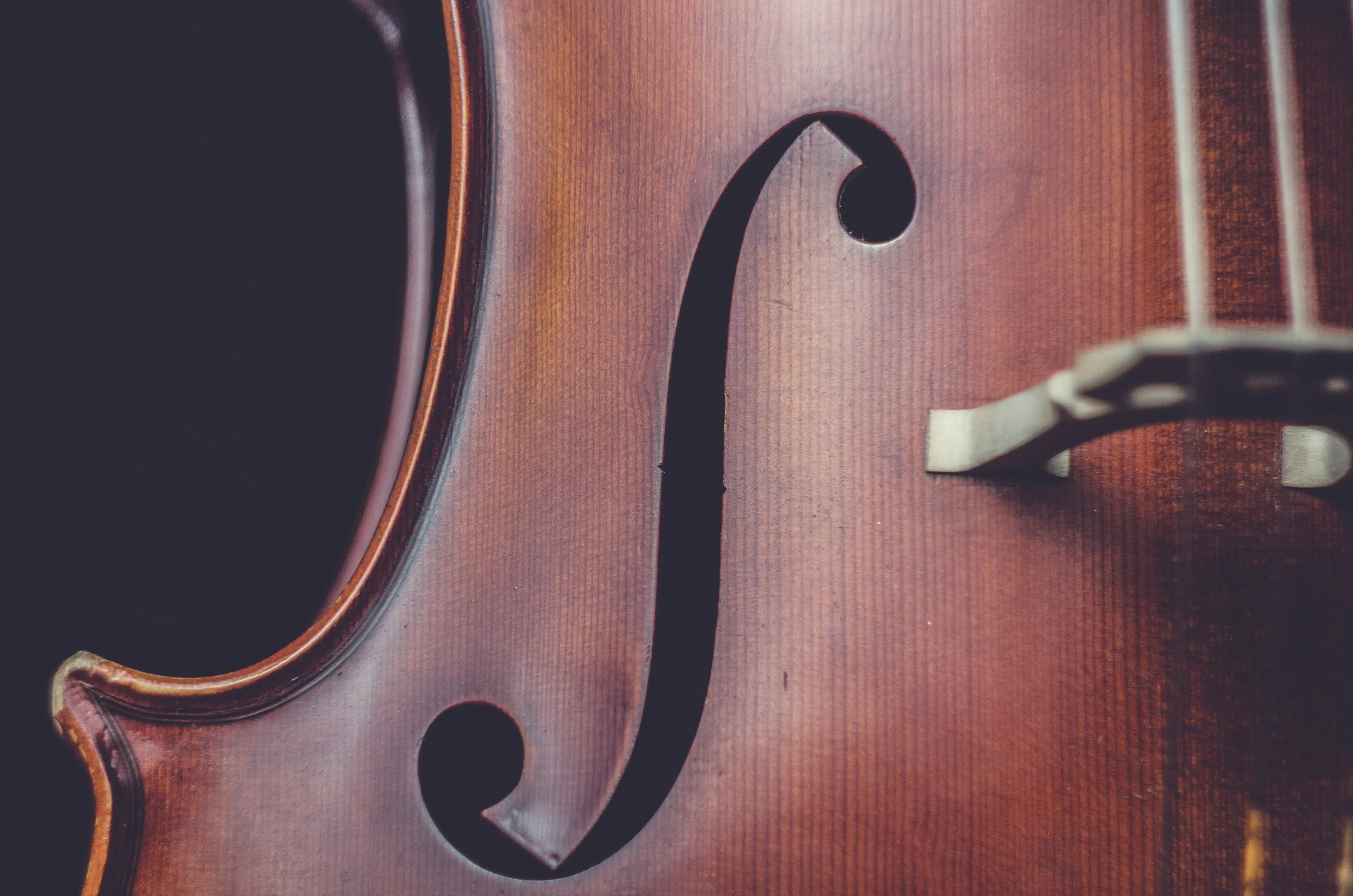 Close-up of a cello with wooden body and strings.