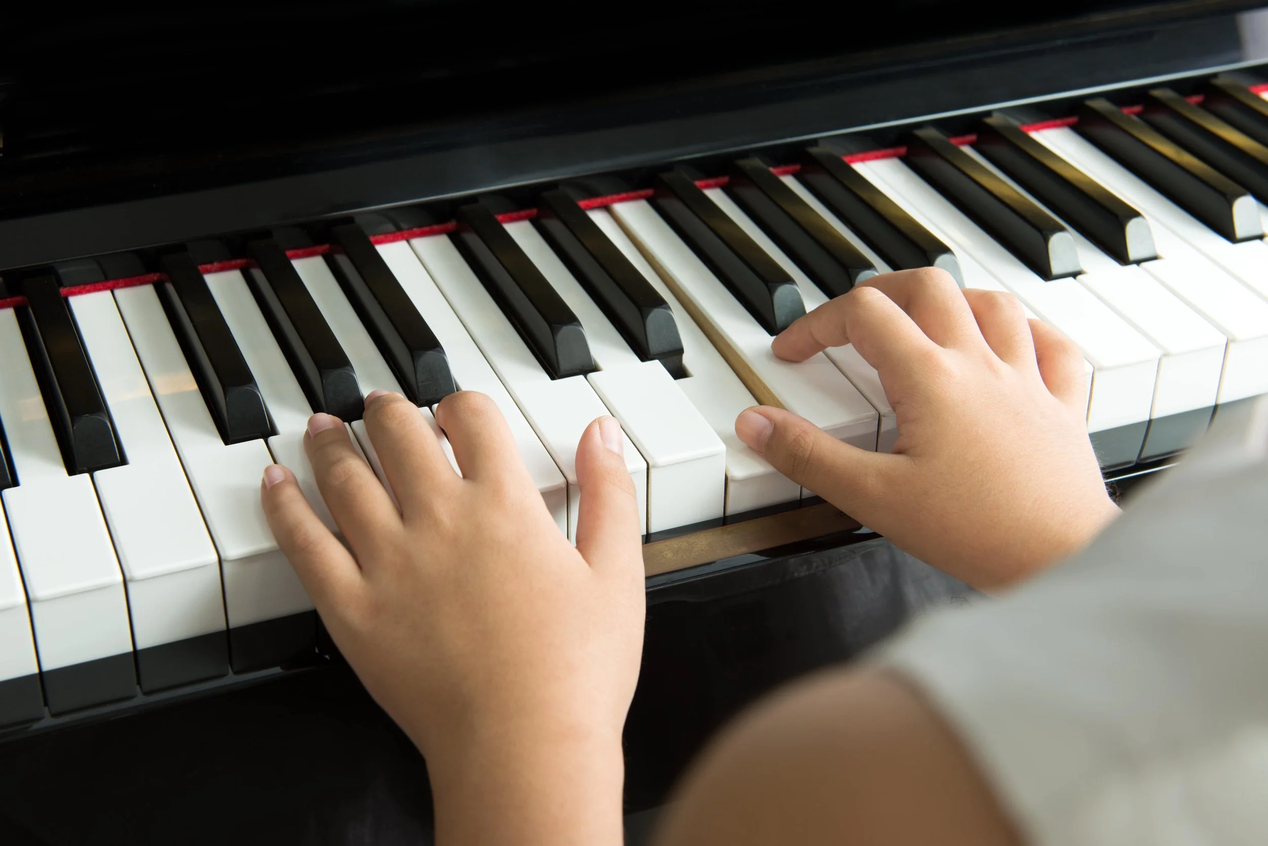 Close-up of child hands playing the piano during a lesson at home.